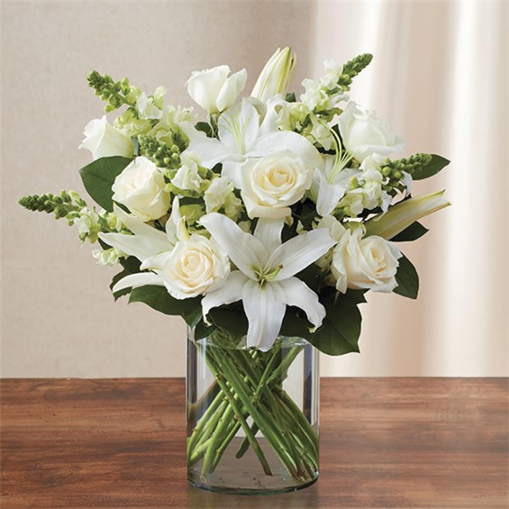 White lilies and roses arranged in a clear glass vase