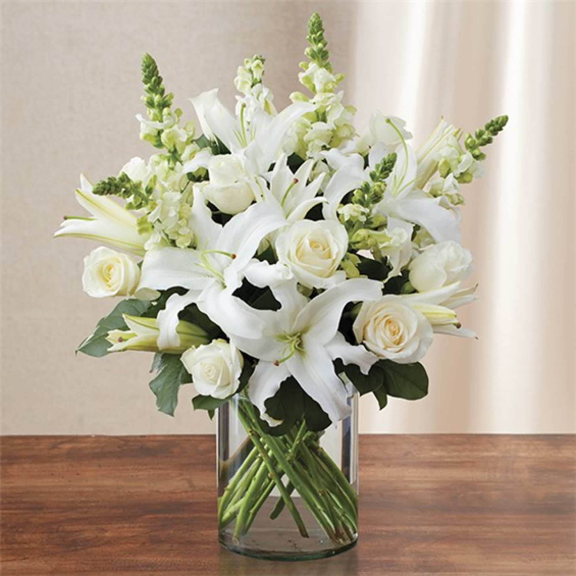 White lilies and roses arranged in a clear glass vase