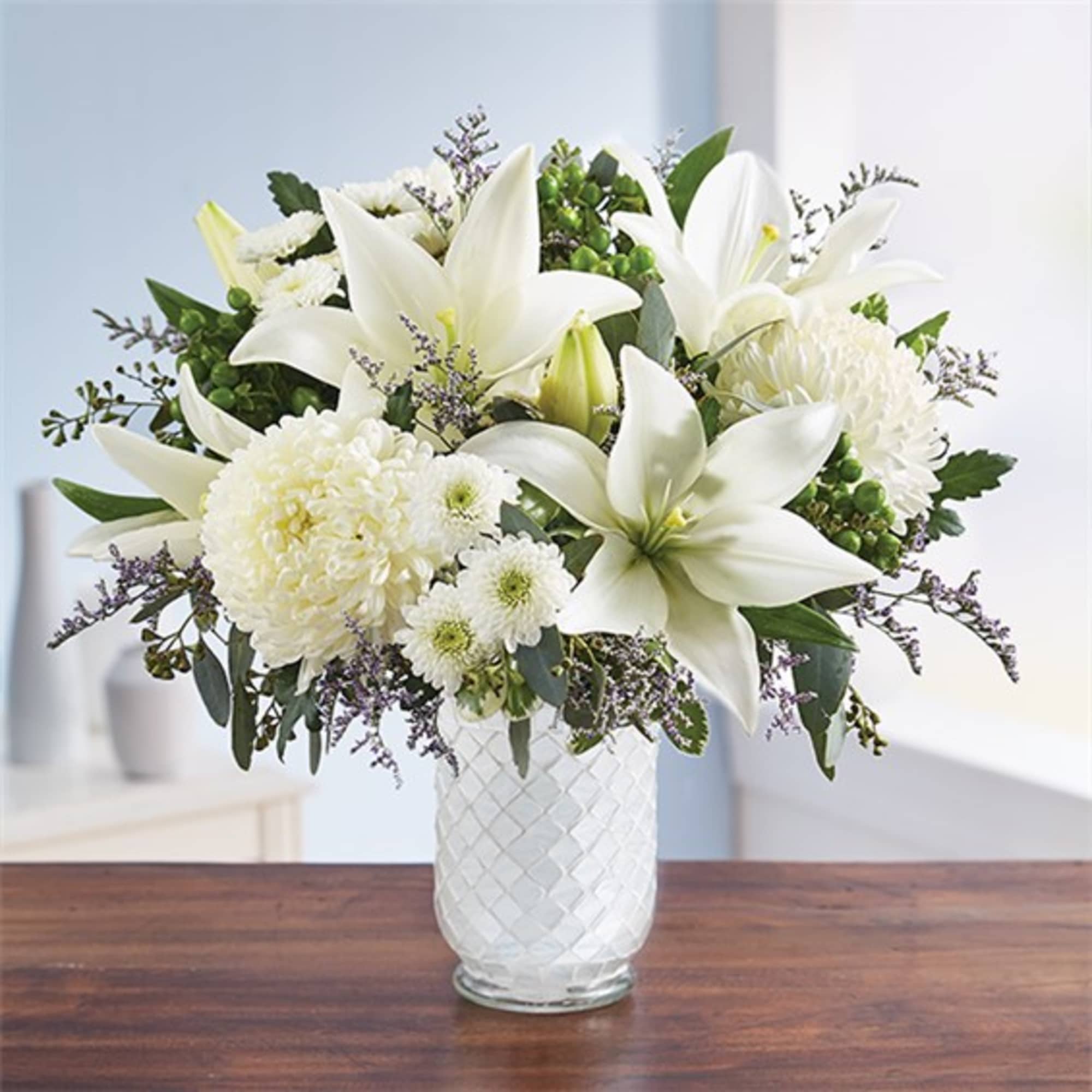 White lilies and chrysanthemums arranged in a clear glass vase