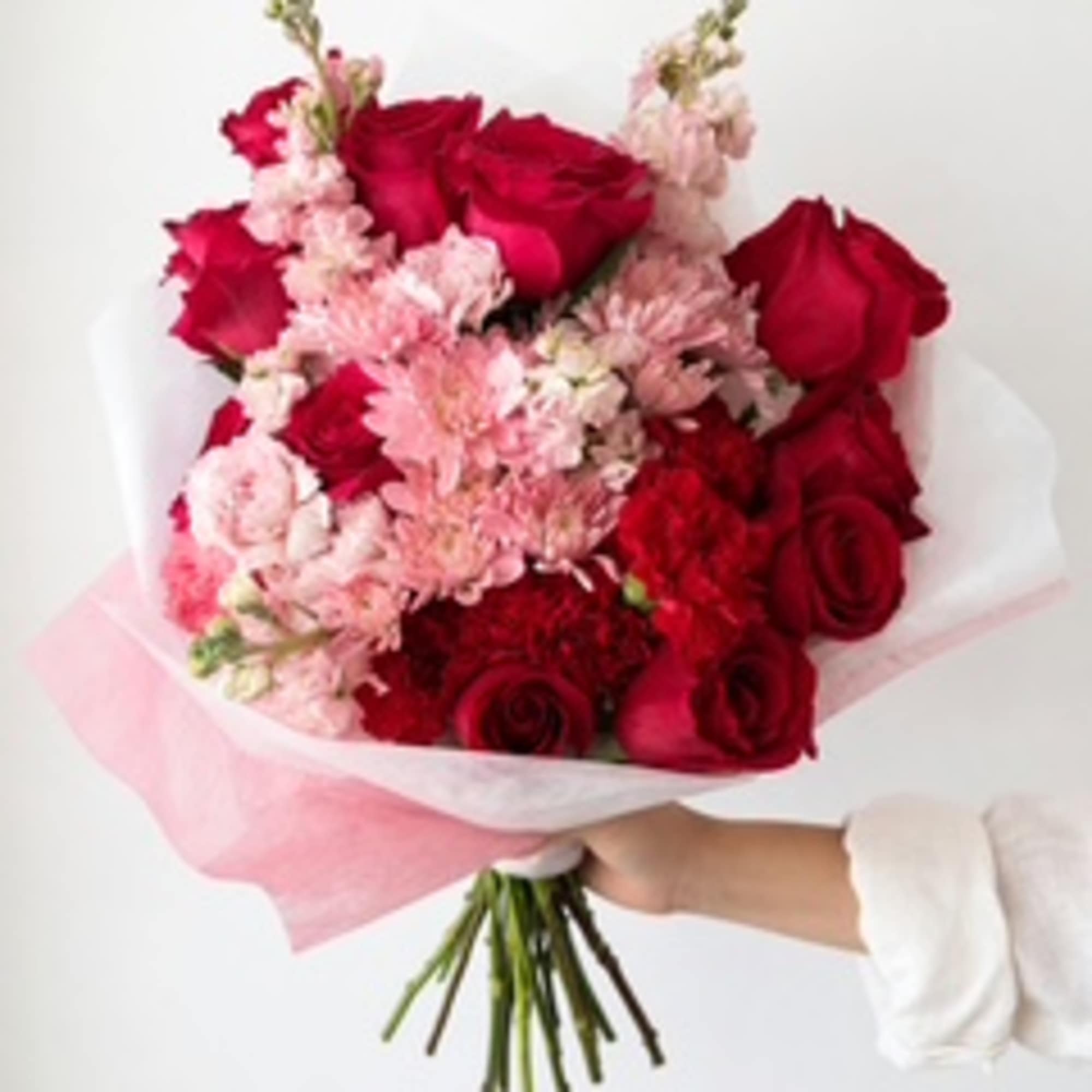 Bouquet of red roses and pale pink flowers wrapped in white and pink paper
