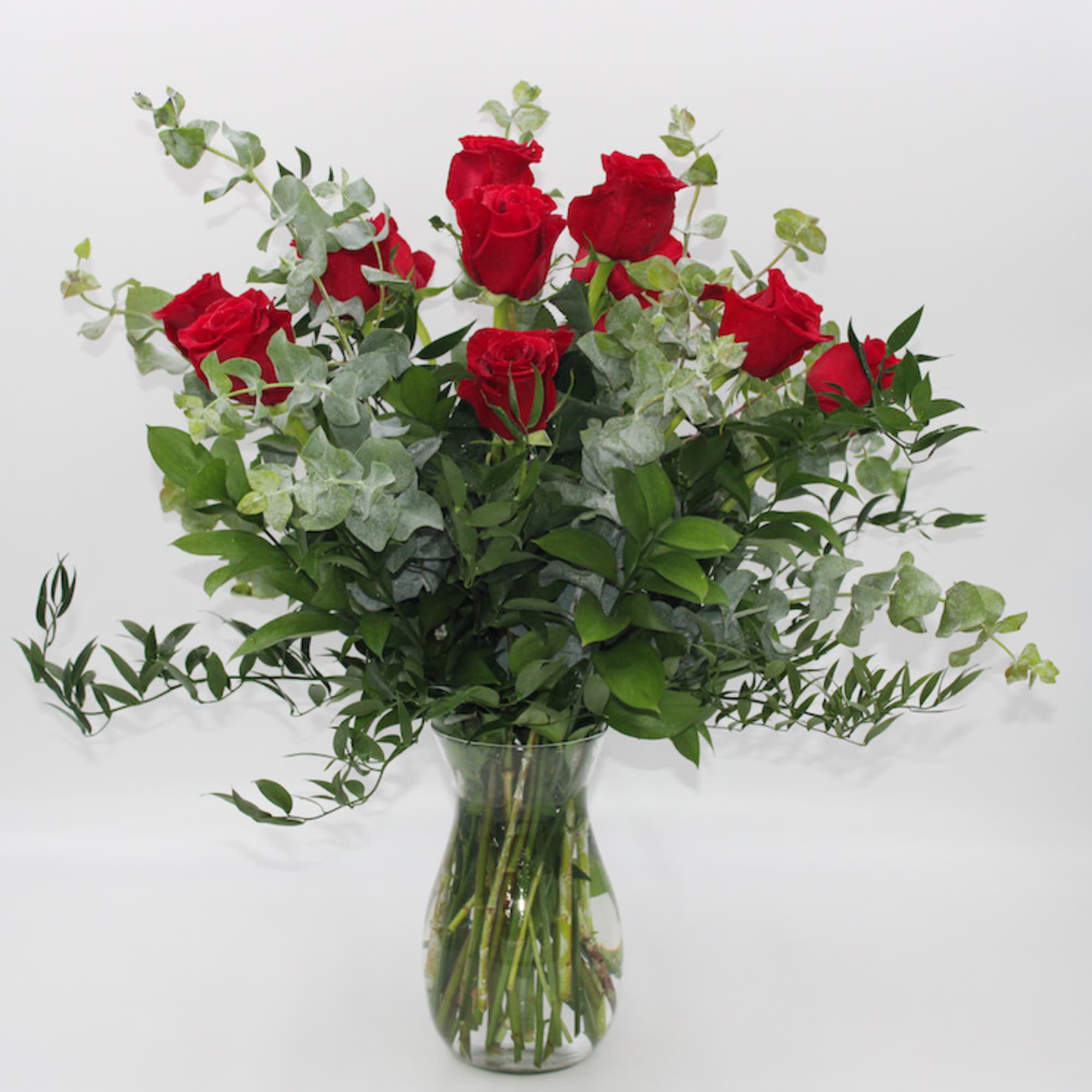 Red roses in a clear glass vase with airy greenery
