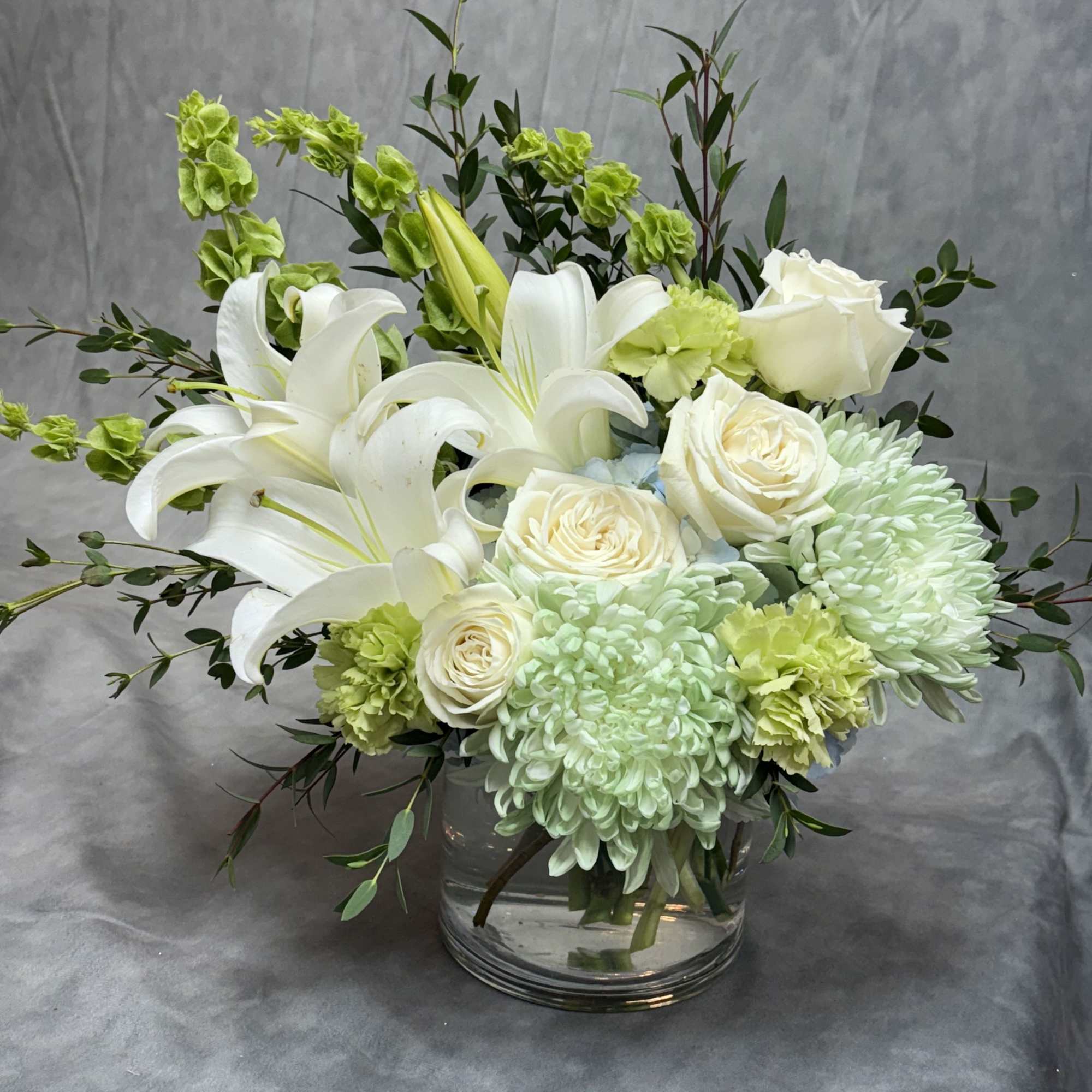 White lilies and pale roses arranged in a clear glass vase