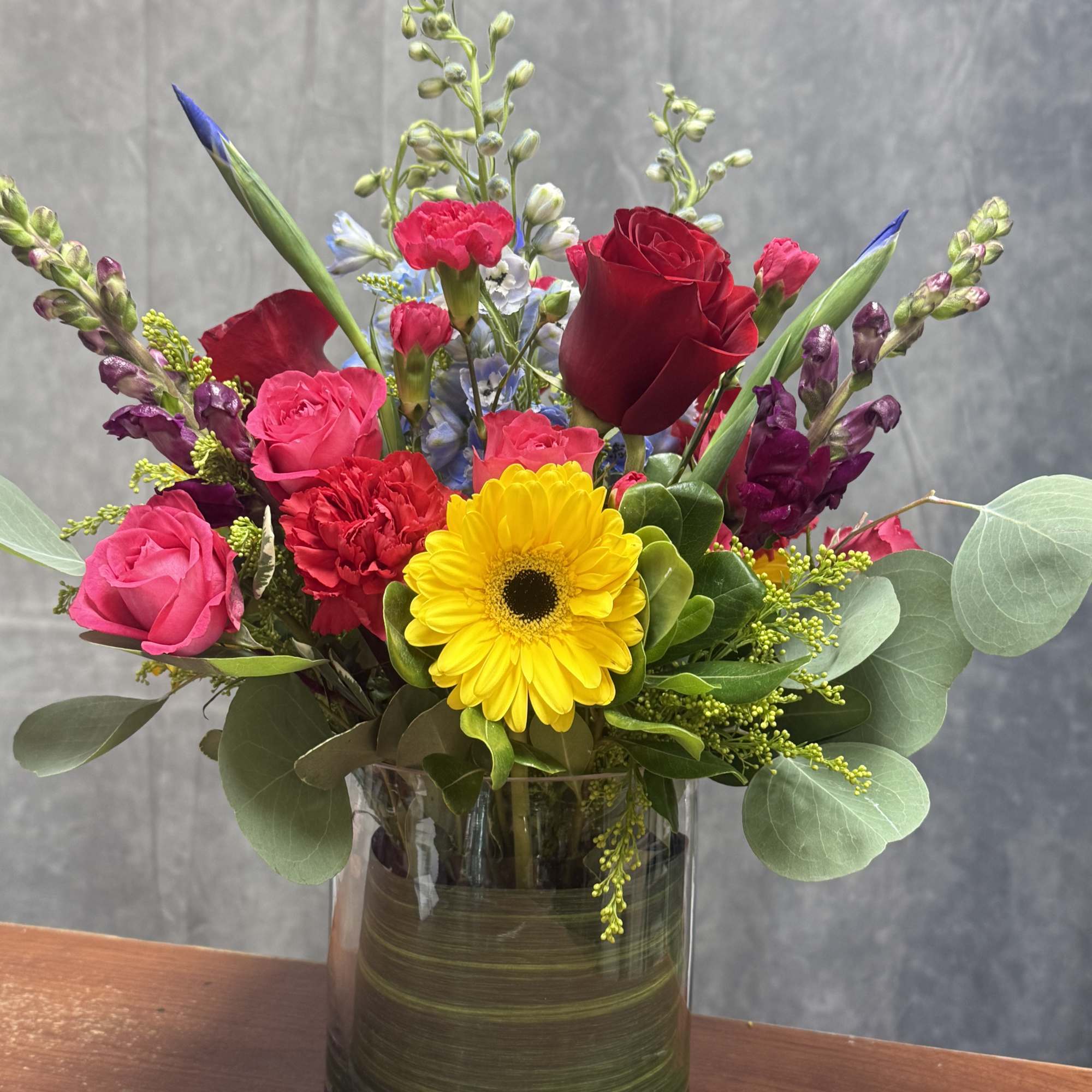 Mixed bouquet in a glass vase with red, pink, yellow, and purple flowers