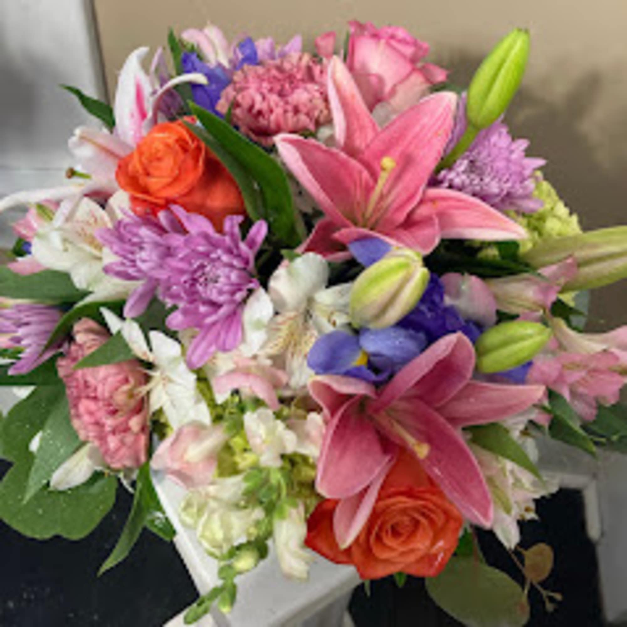 Mixed bouquet with pink lilies, orange roses, and purple flowers