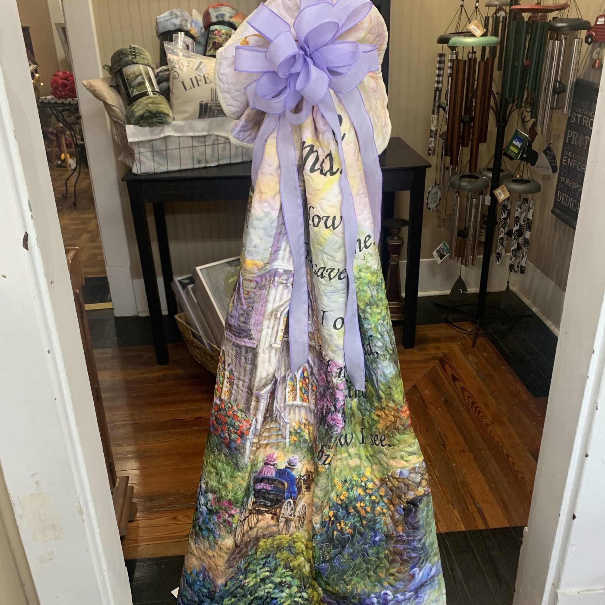Quilted decorative throw draped over a stand with a lavender bow