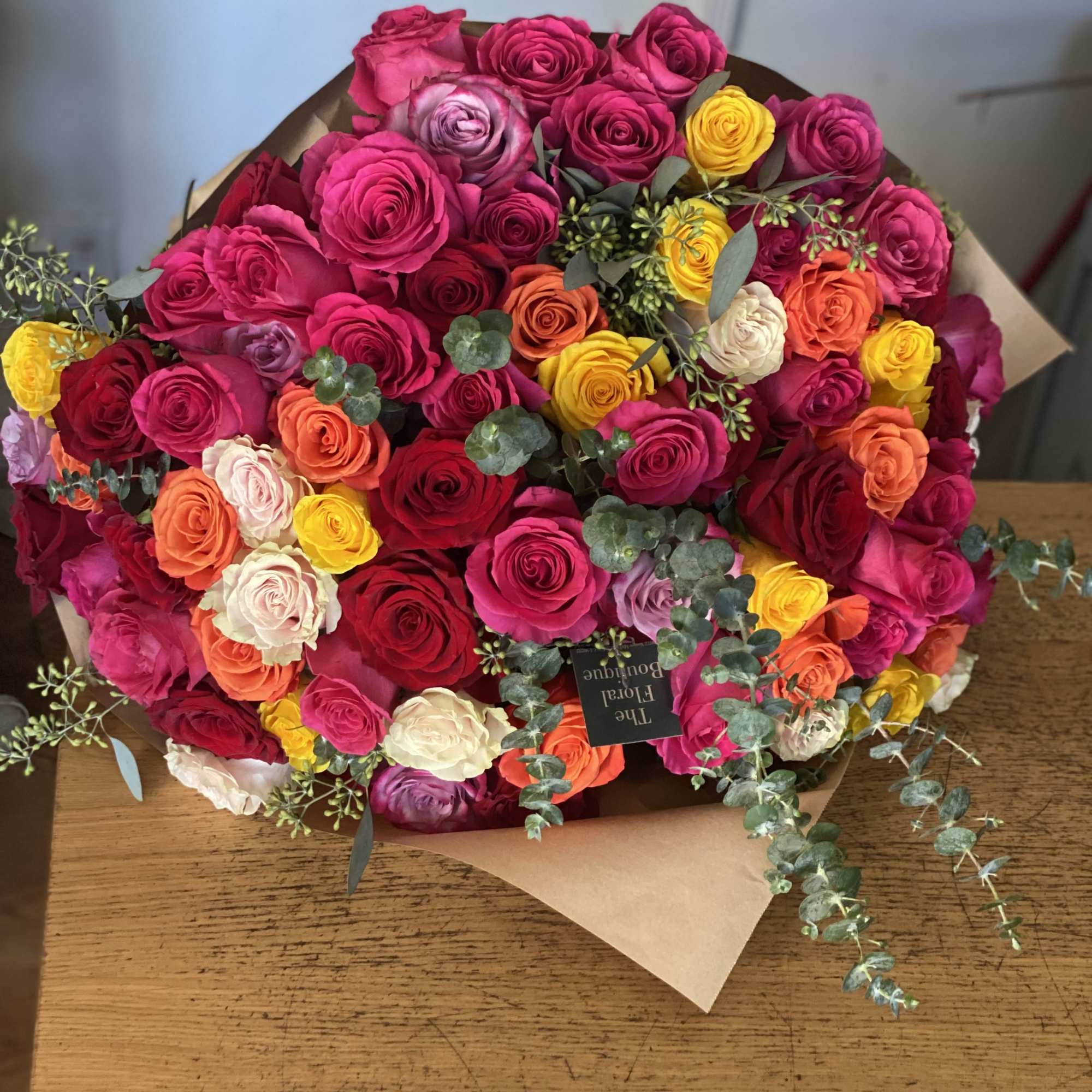 Bouquet of multicolored roses wrapped in brown paper
