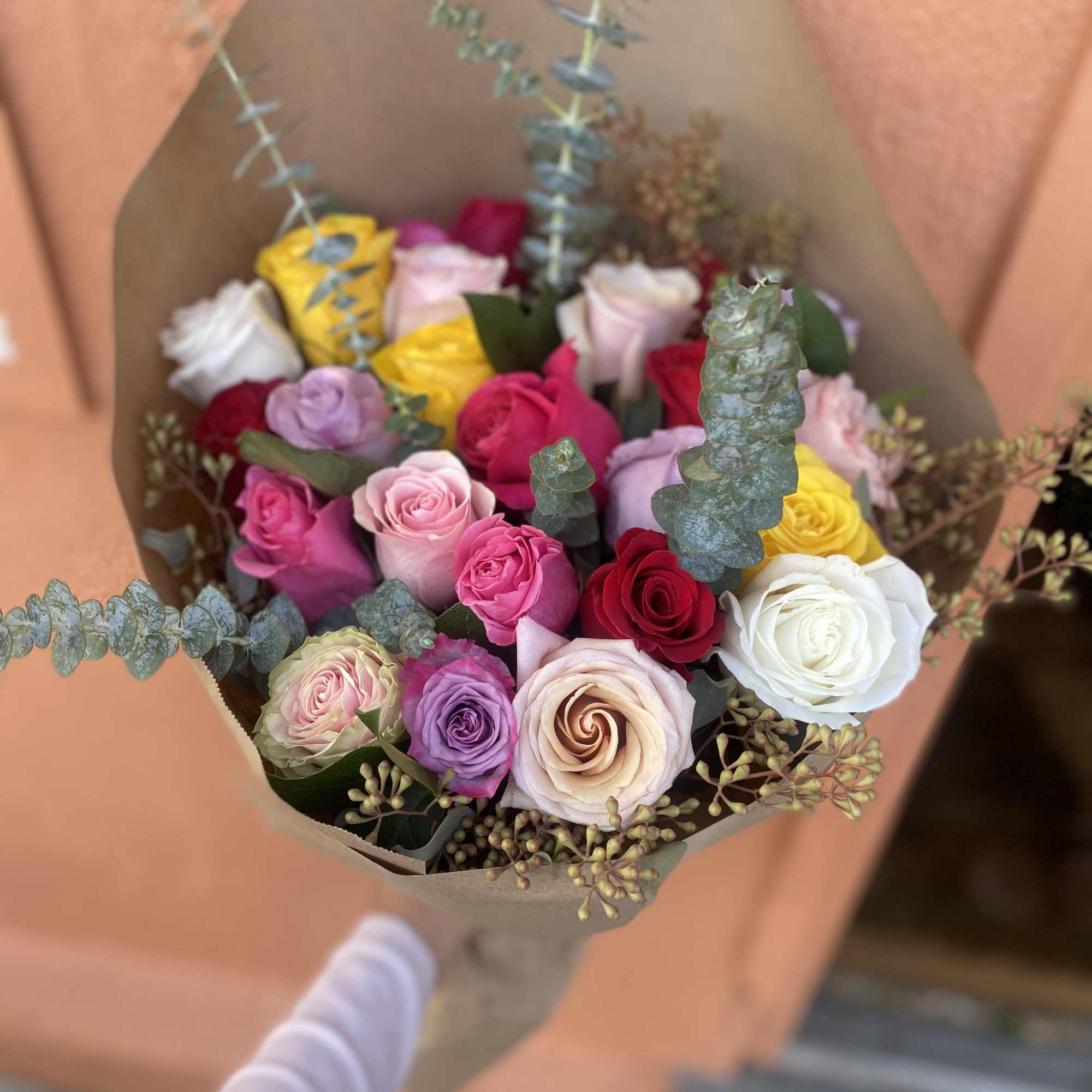 Bouquet of multicolored roses wrapped in brown paper