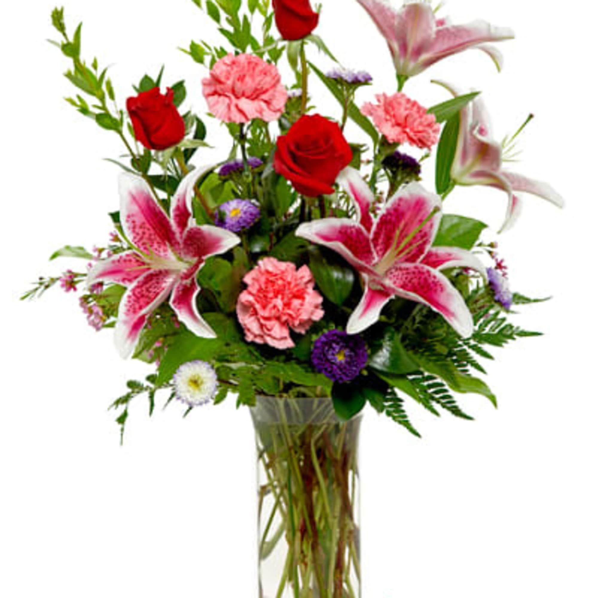 Tall vase arrangement with red roses, pink lilies, pink carnations, and purple accent flowers