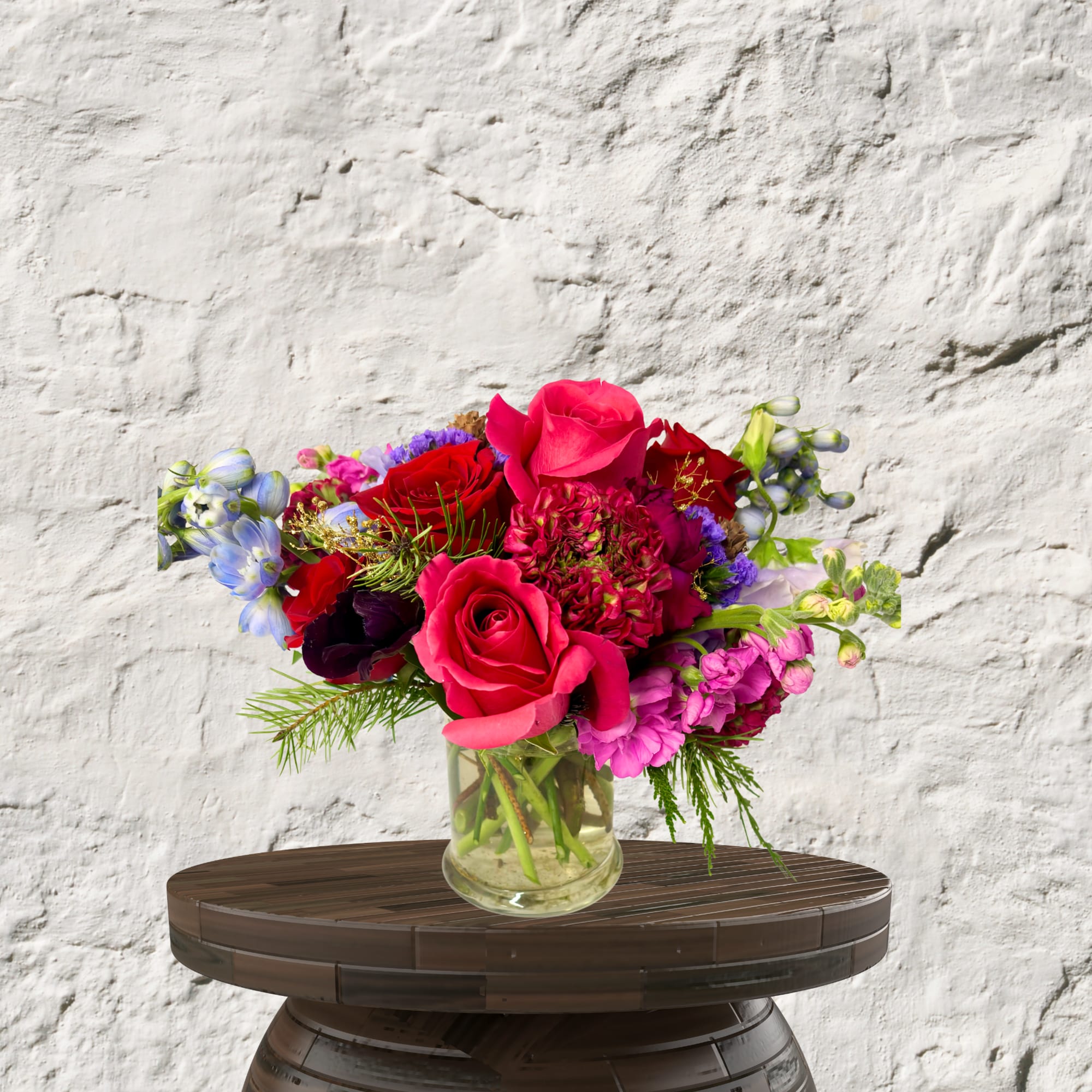 Bright mixed bouquet of roses and purple flowers in a glass vase