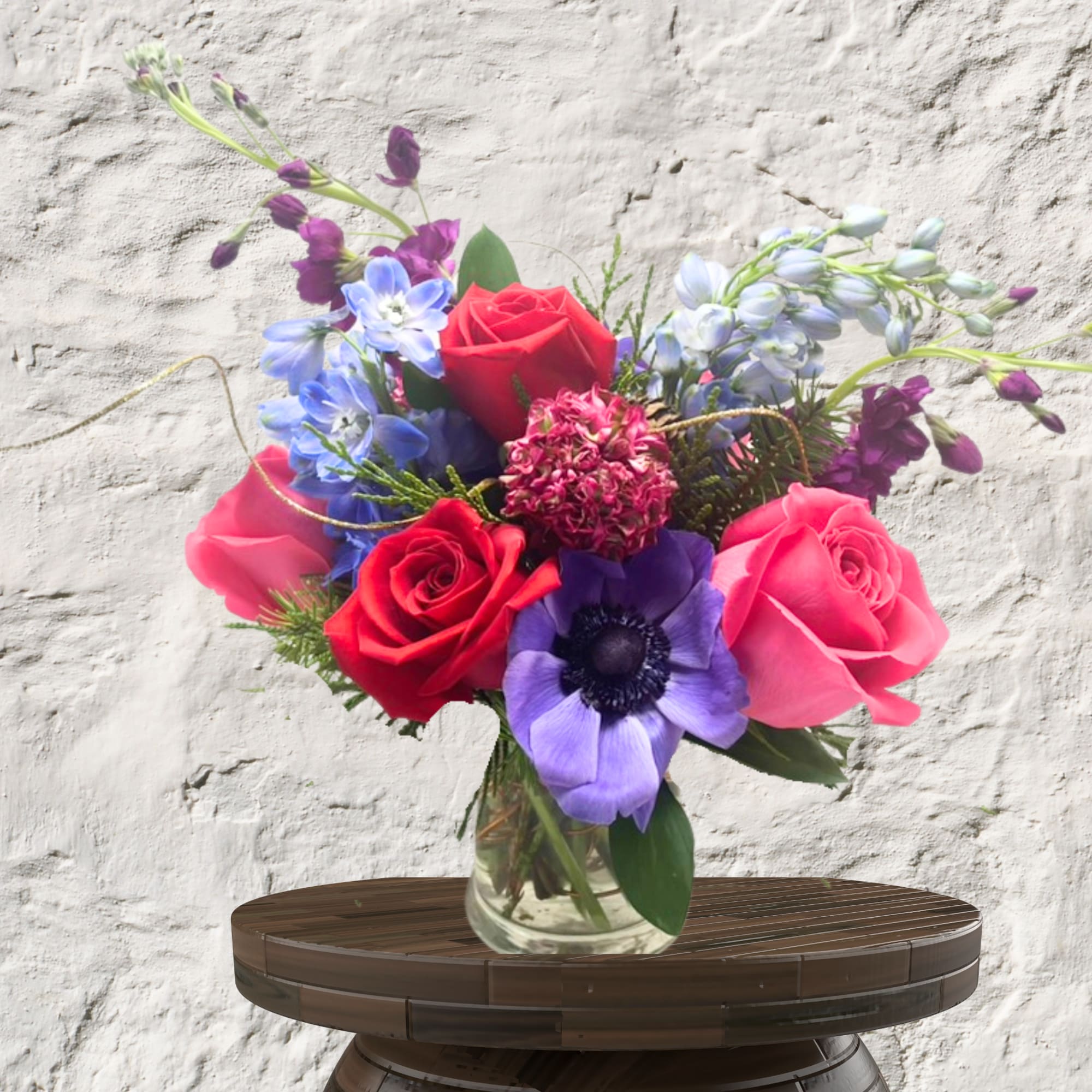Bouquet of red, pink, and purple flowers in a clear glass vase