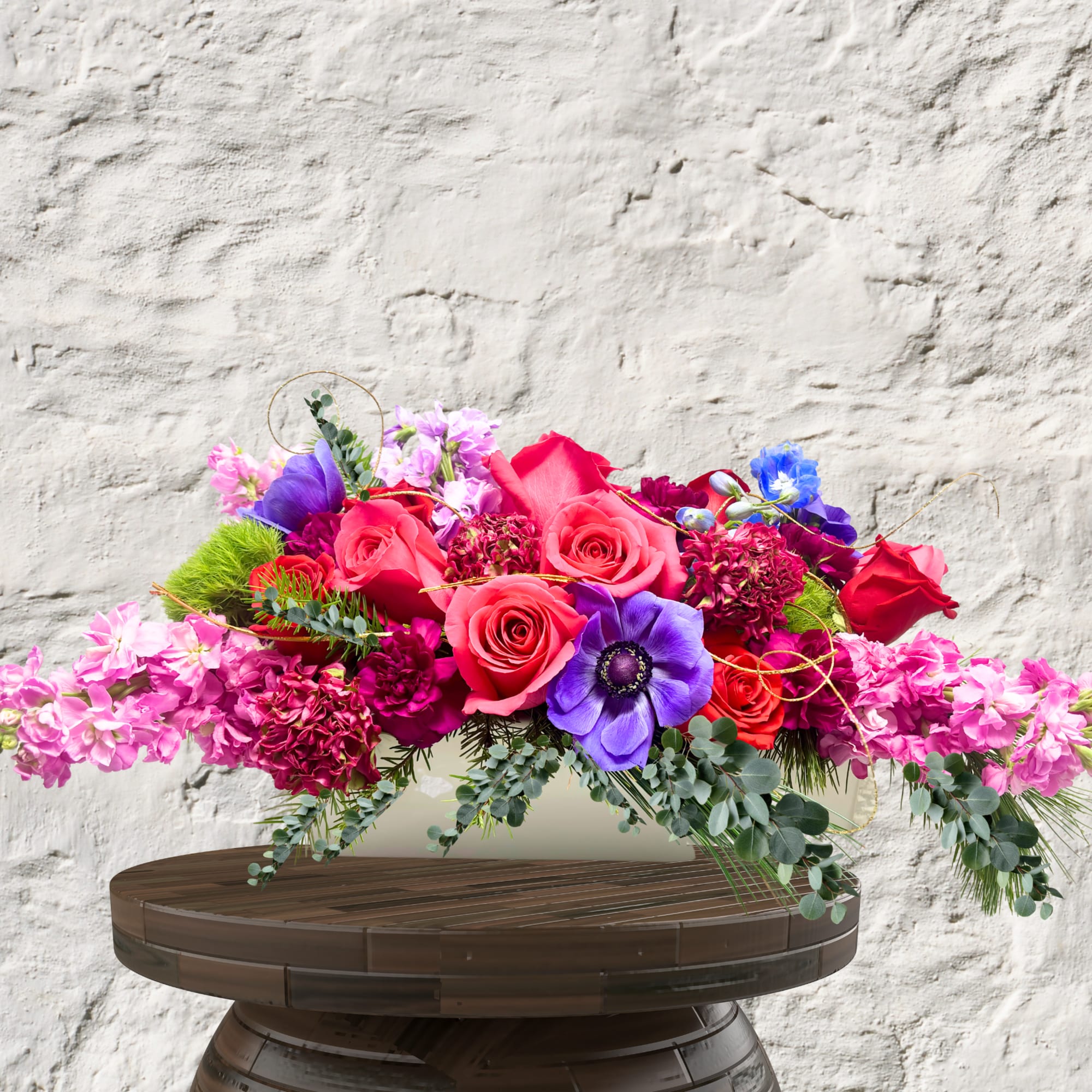 Bright mixed bouquet with pink and purple flowers in a low container