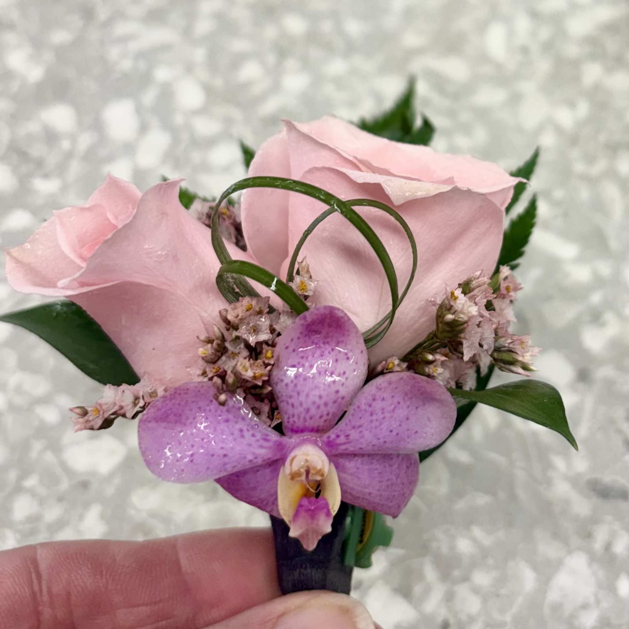 Pink rose and purple orchid boutonniere with small filler flowers