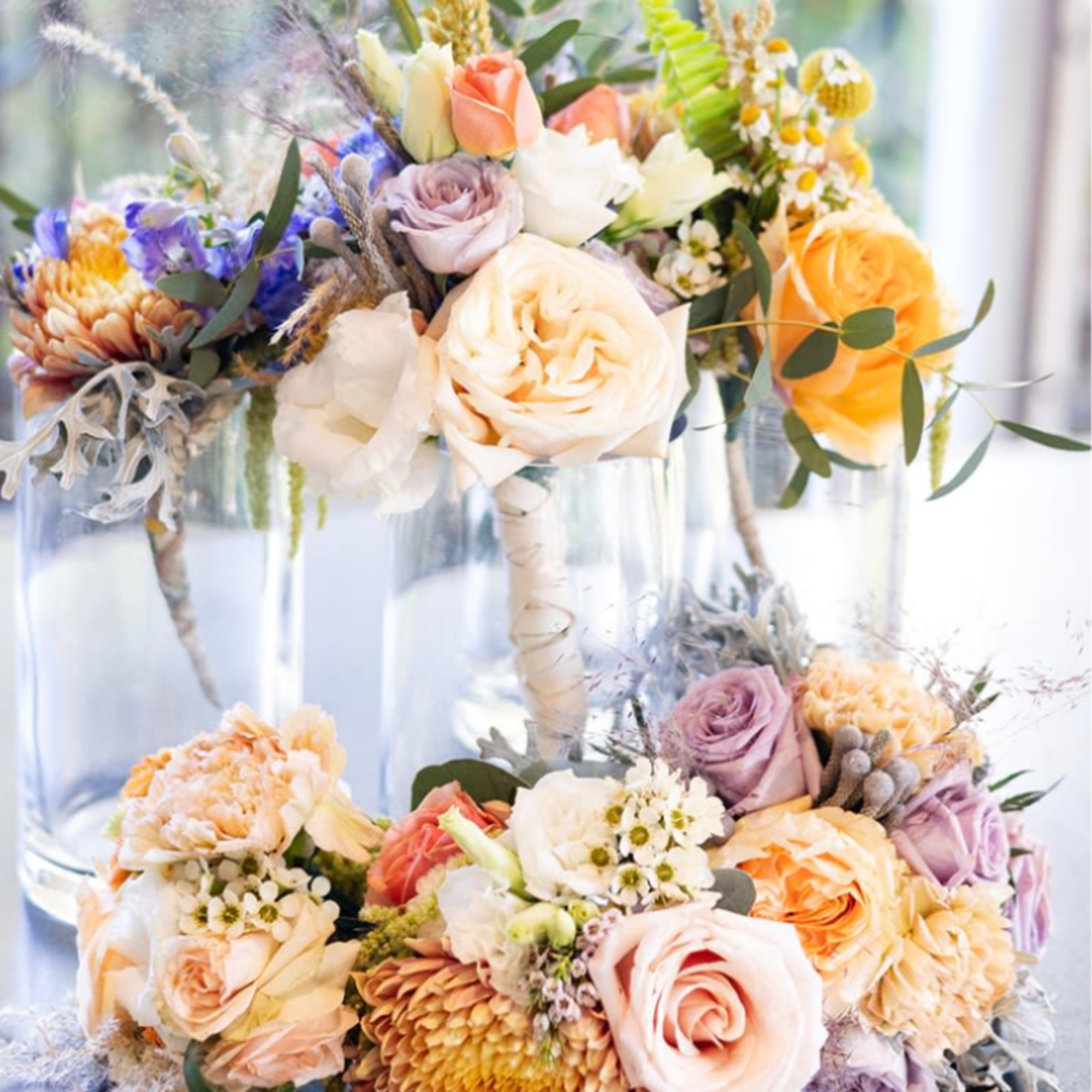 Pastel floral arrangements in clear glass vases with roses and mixed blooms
