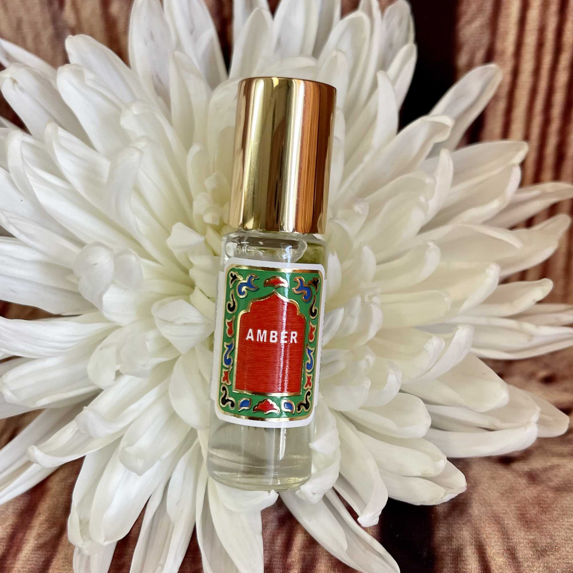 White chrysanthemum with a small amber perfume bottle in front