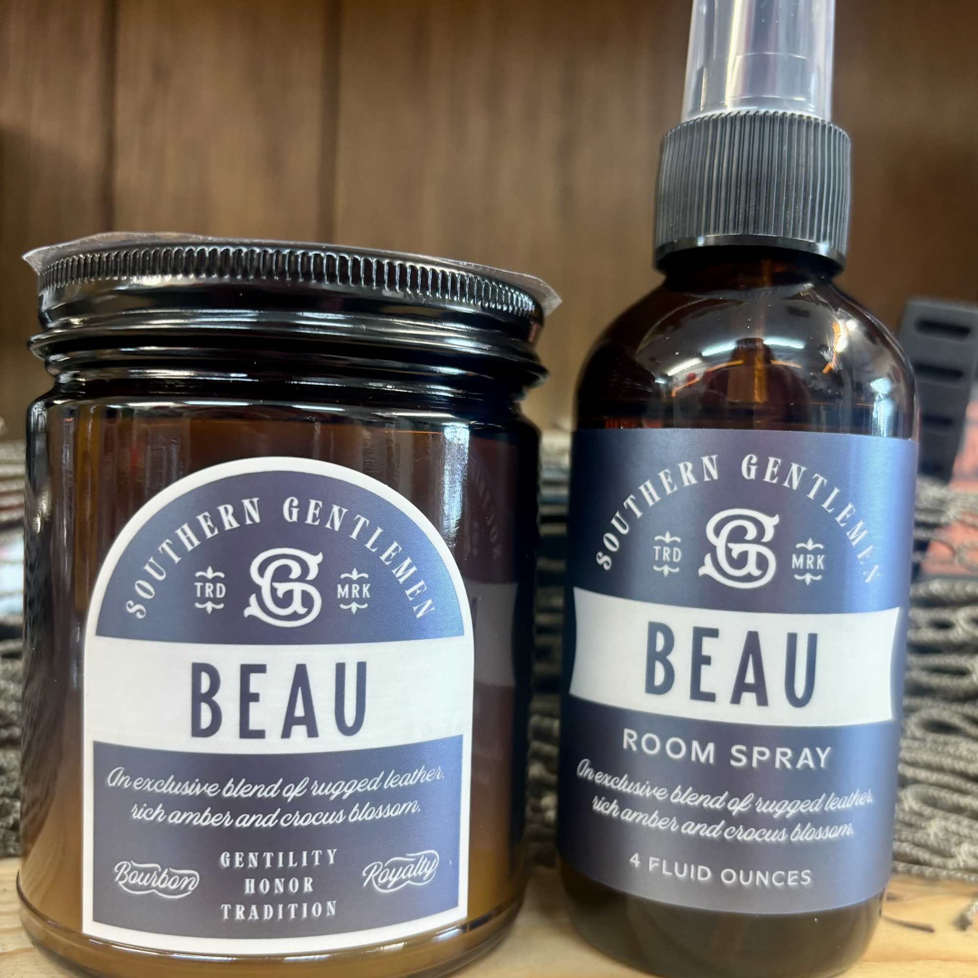Two Beau room fragrance products in amber bottles on a wooden surface.