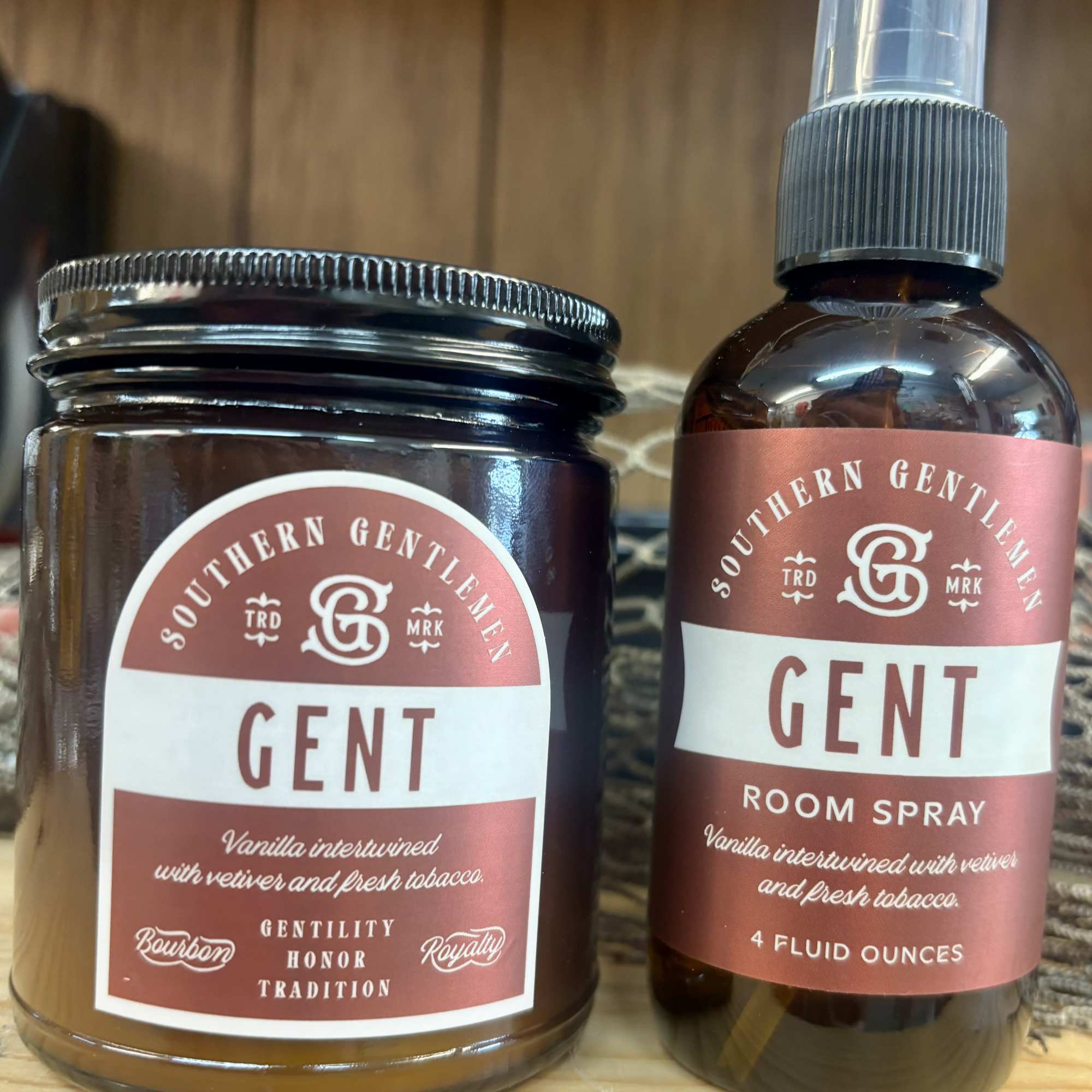 Two amber room-scent products with rose labels on a wooden surface.