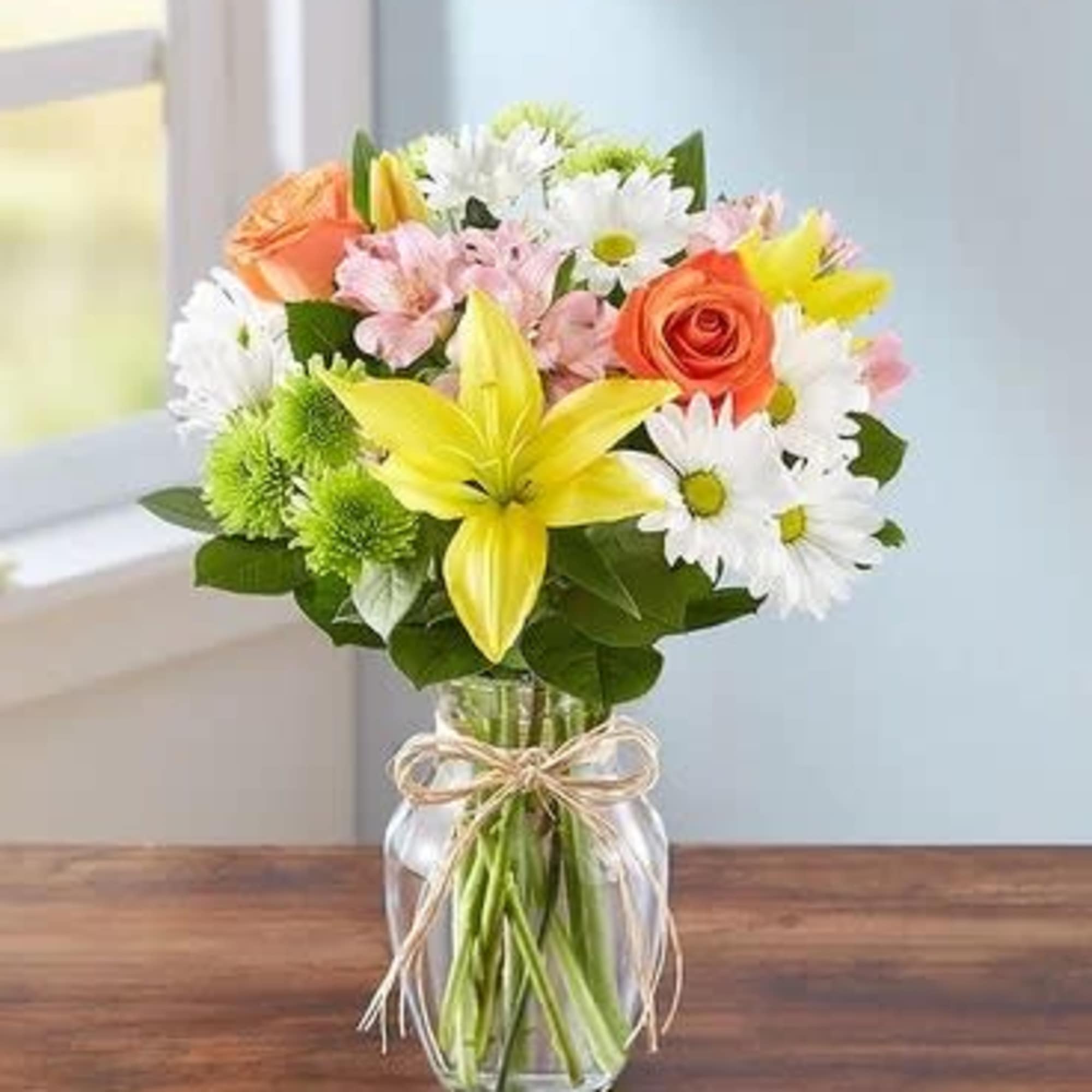 Mixed bouquet of lilies, roses, and daisies in a glass vase