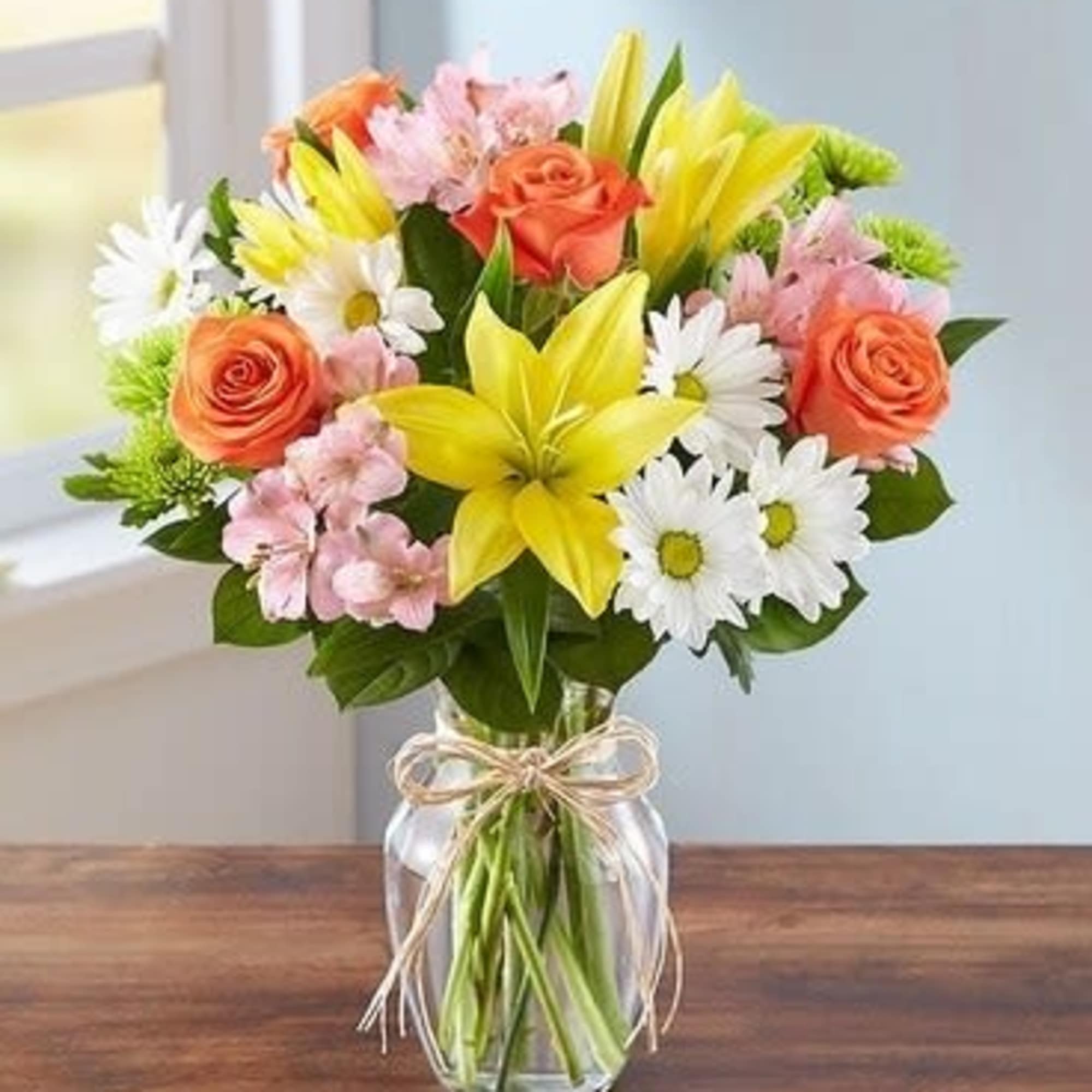 Bouquet of yellow lilies, orange roses, and white daisies in a glass vase, photo 2 of 3