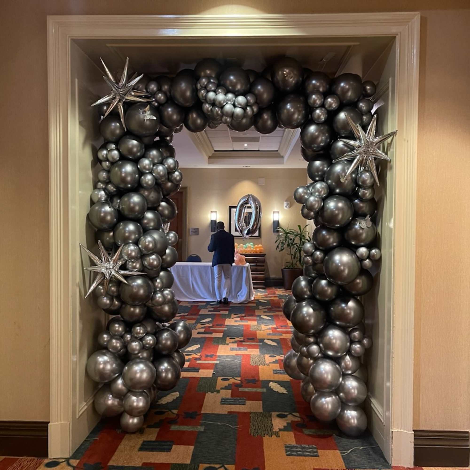 Silver and black balloon arch framing a doorway with star balloons
