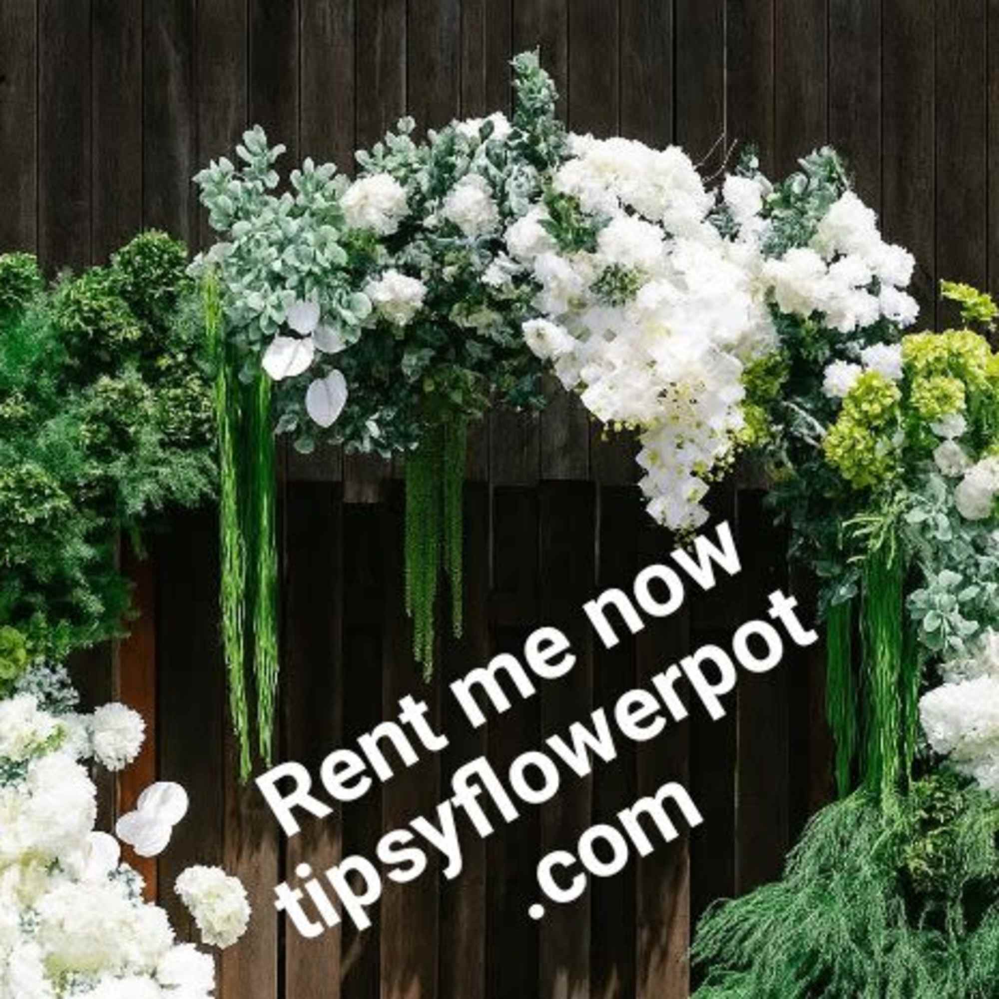 Large floral arch with white and green flowers against a dark wood wall