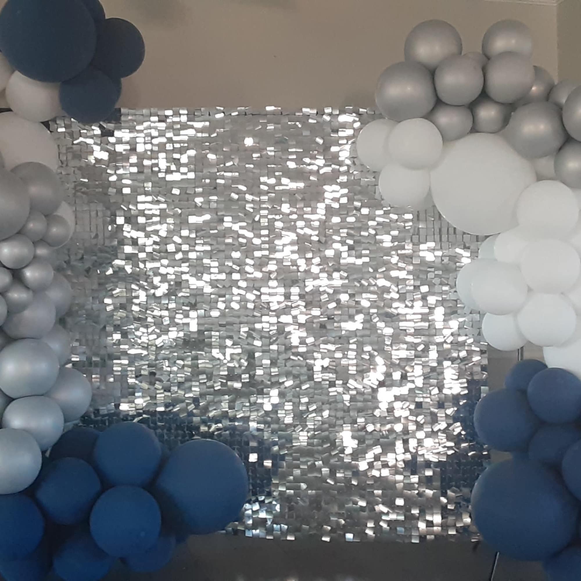 Balloon arch in white, silver, and navy around a silver sequin backdrop