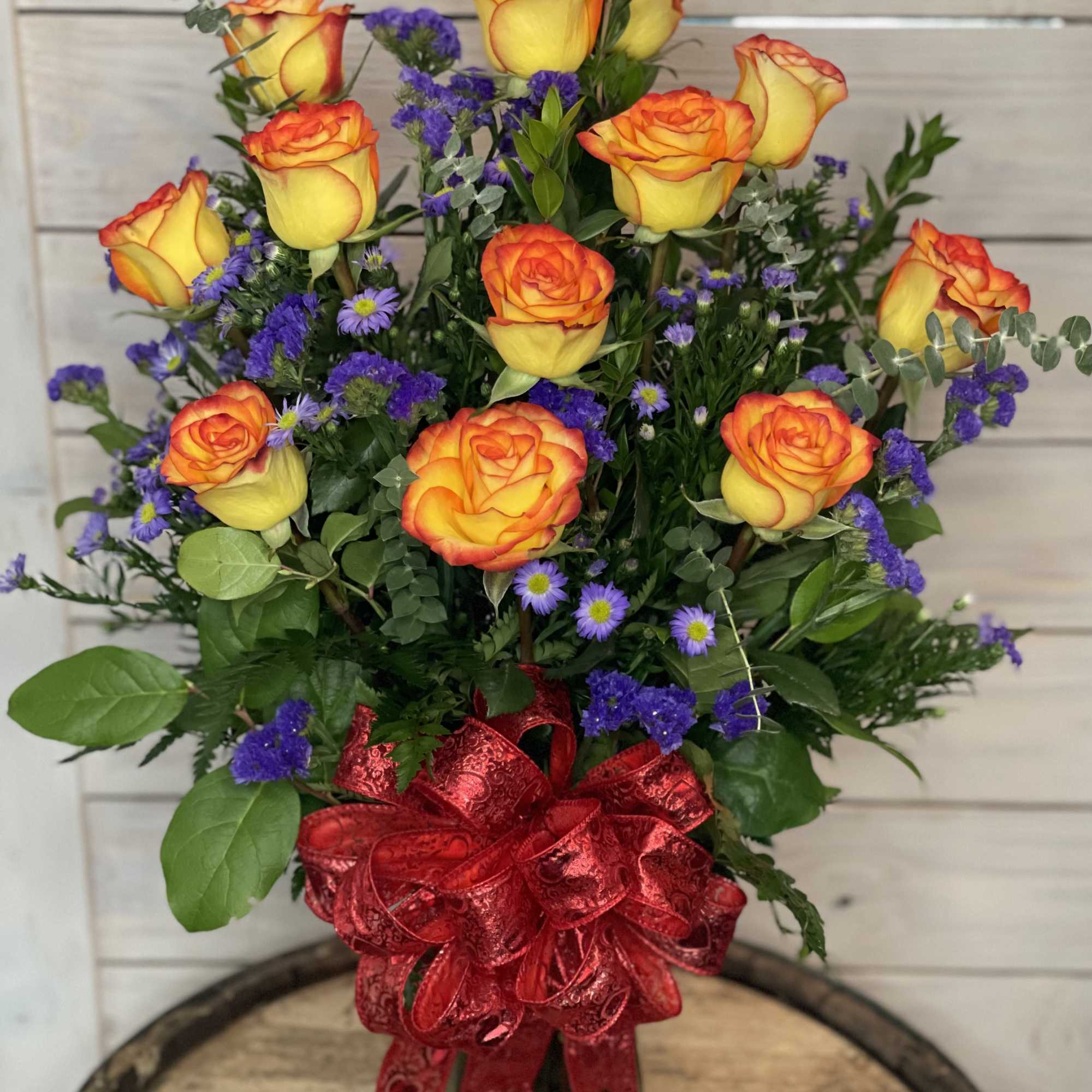 Yellow and orange roses in a glass vase with a red bow