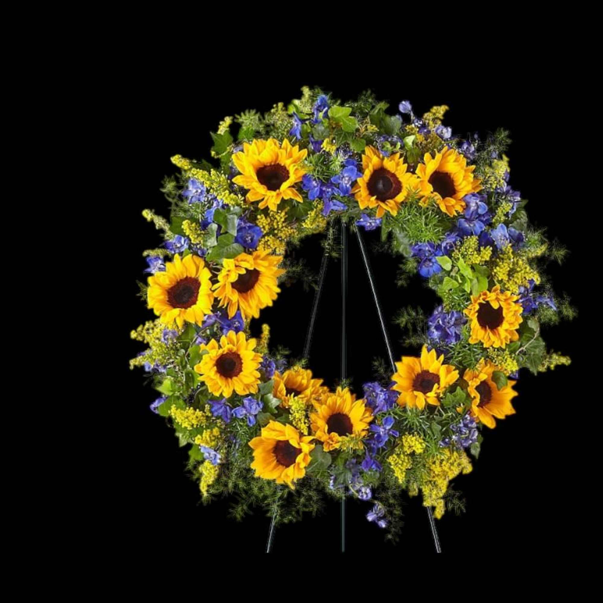 Sunflower wreath with blue and yellow flowers on a black stand