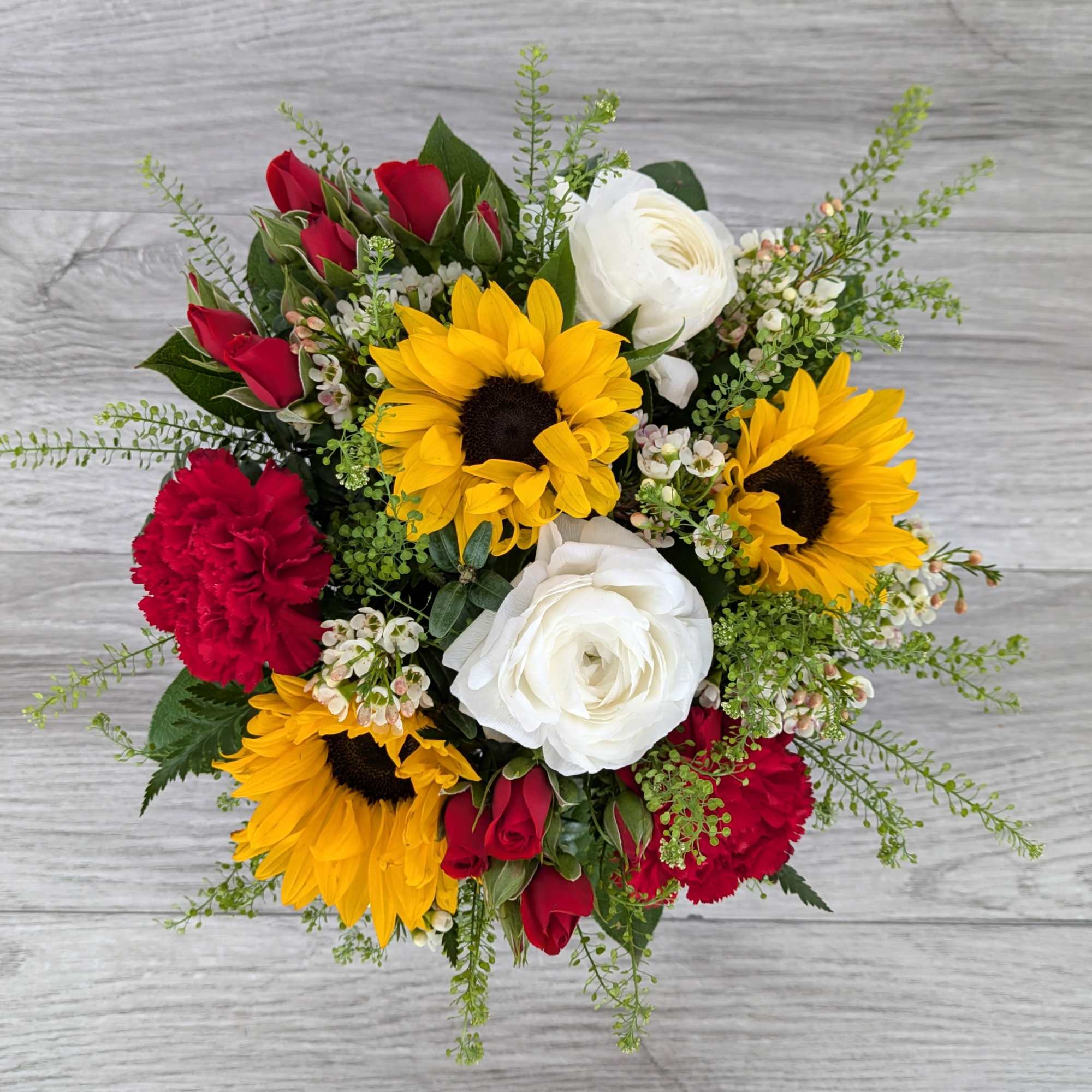 Bouquet of sunflowers, red roses, white ranunculus, and red carnations