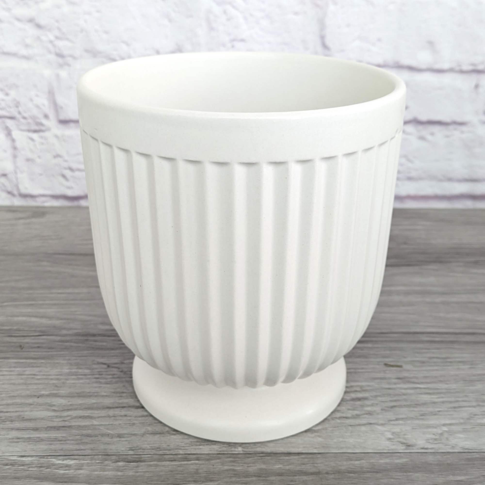 White ribbed ceramic planter on a pedestal base