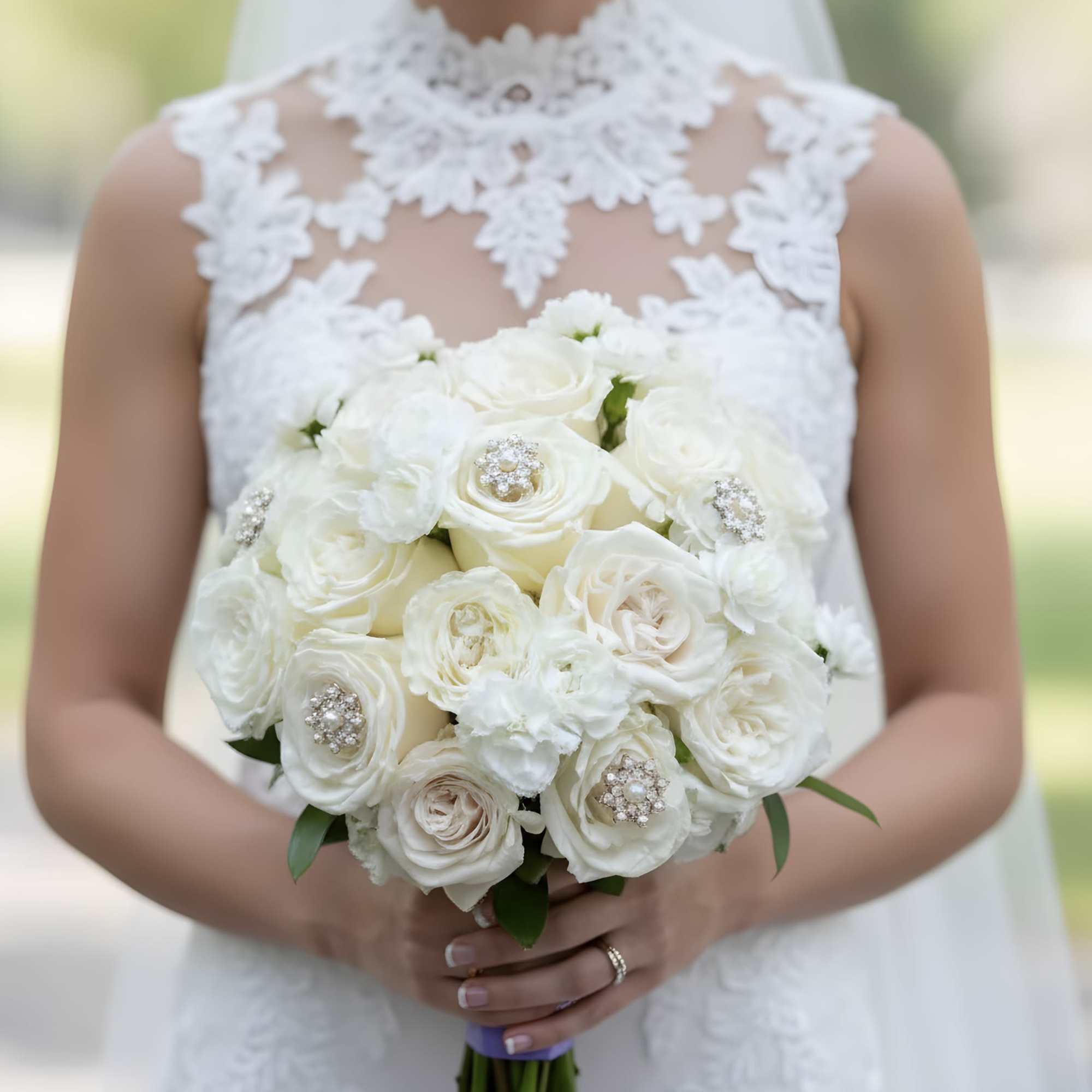 Bride holding a white rose bouquet with jeweled accents