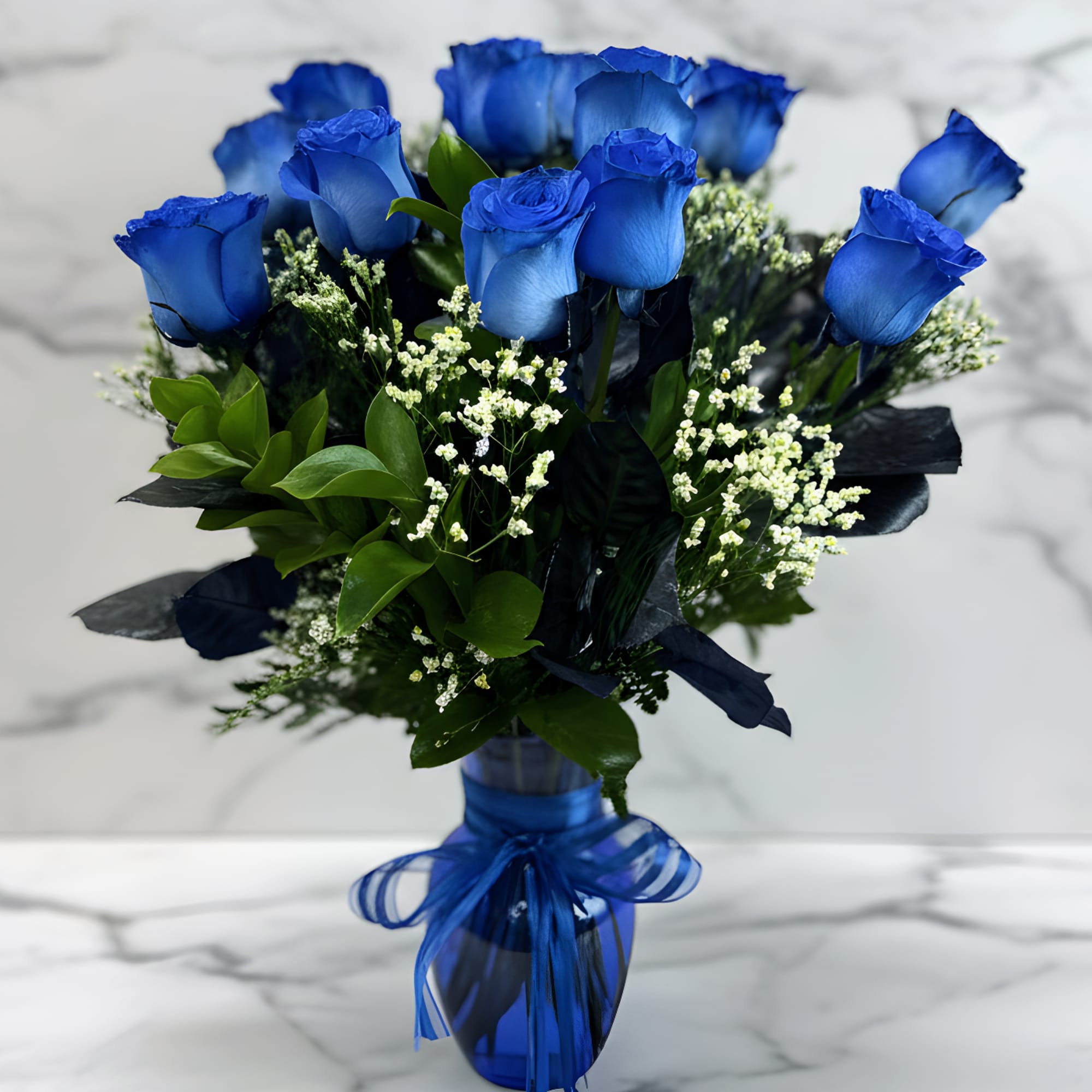 Blue roses in a glass vase with a blue ribbon