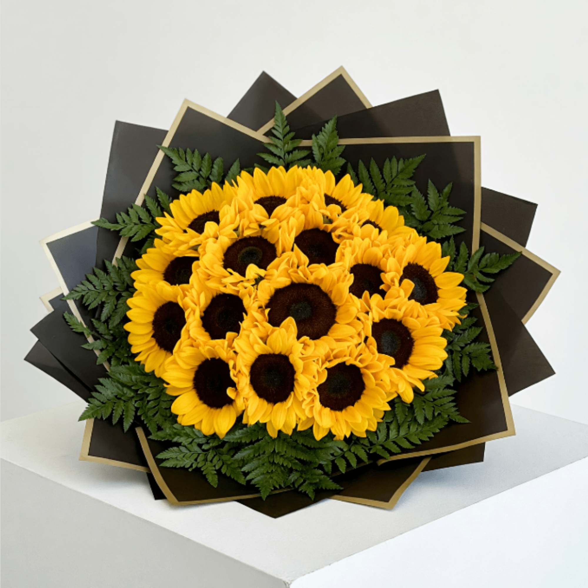 Bouquet of yellow sunflowers with dark centers and fern accents