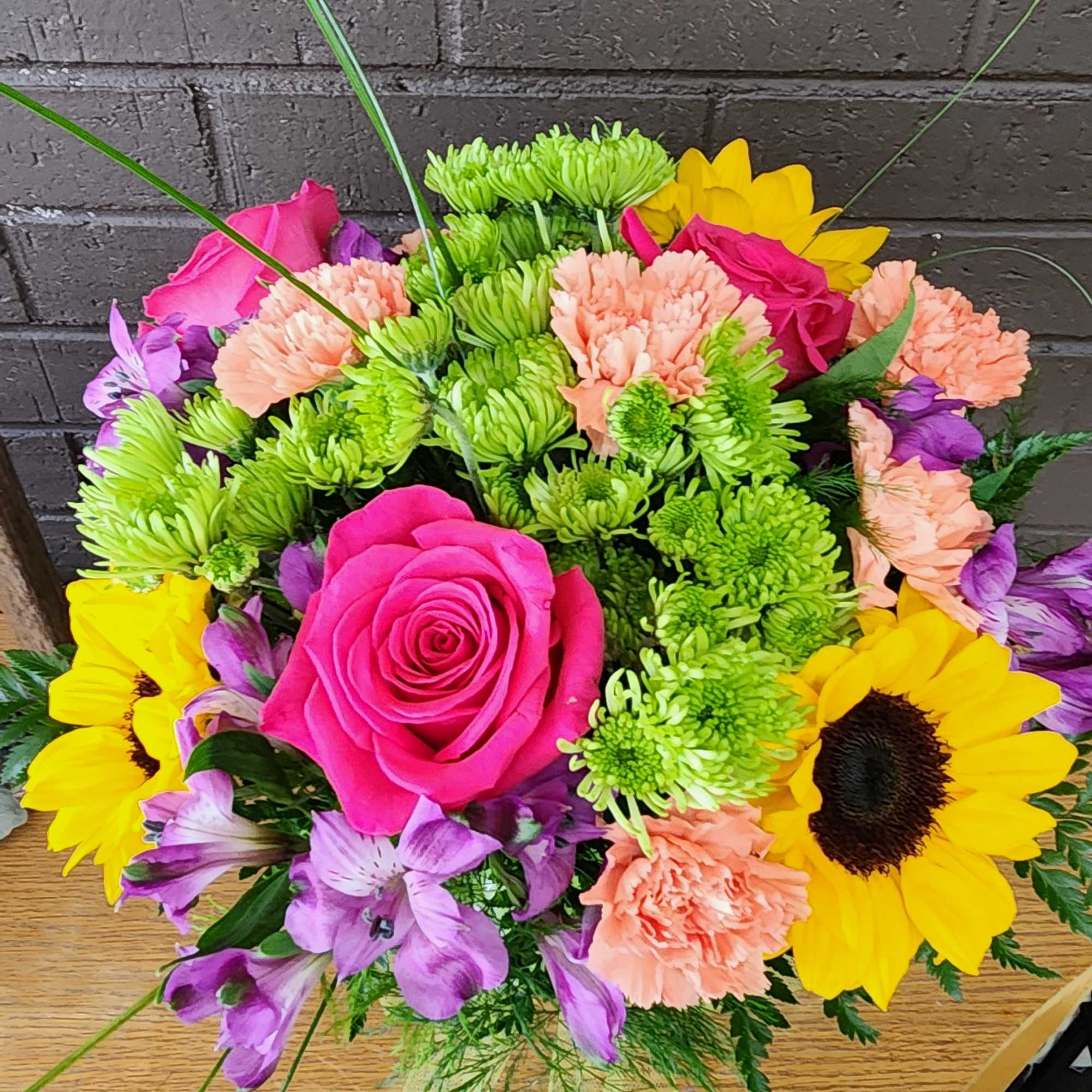 Bright mixed bouquet with pink roses, sunflowers, and green chrysanthemums