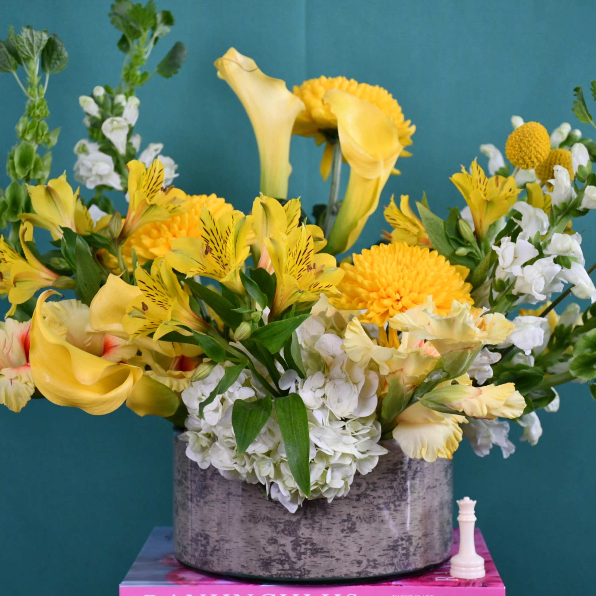 Yellow and white floral arrangement in a gray container