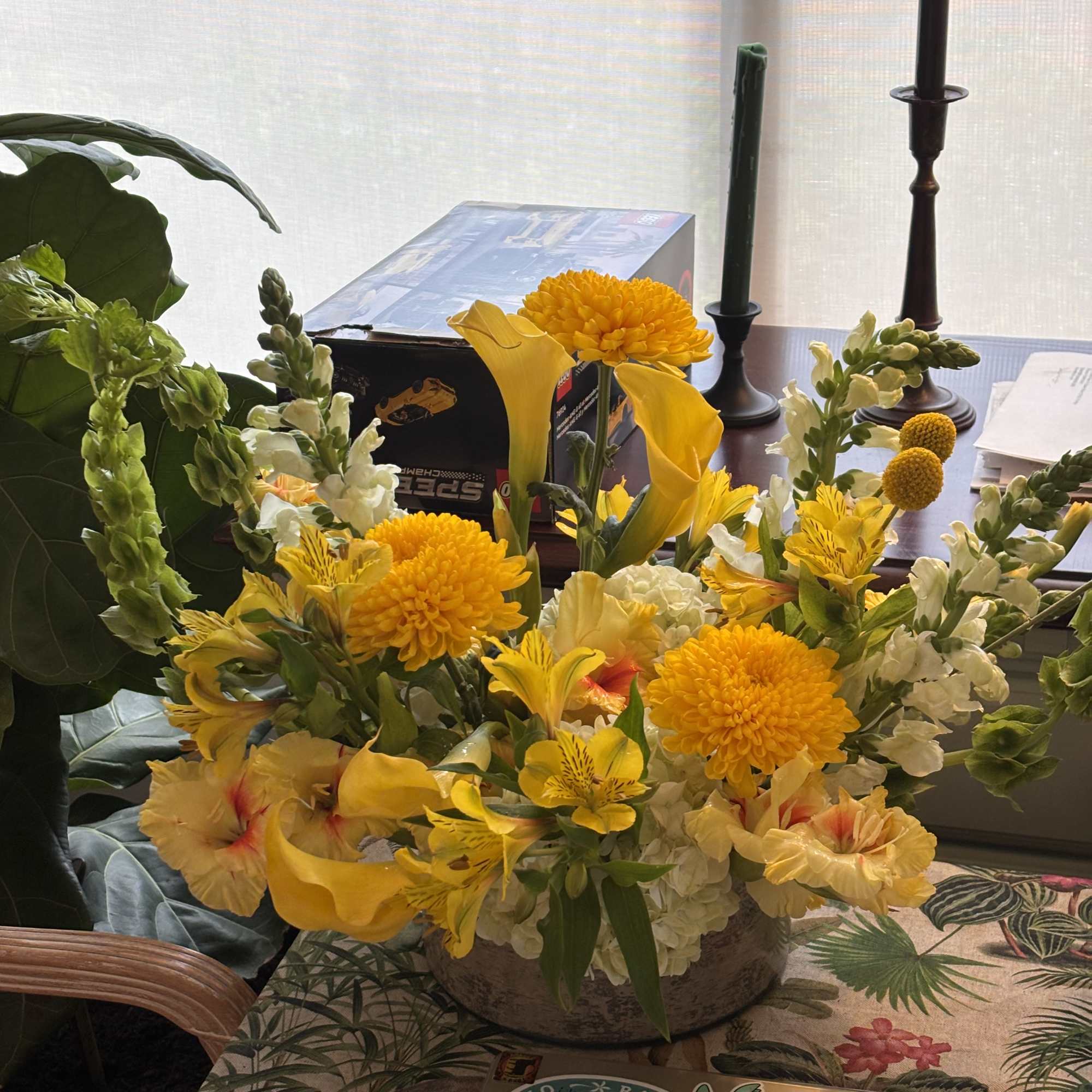 Yellow floral arrangement in a low bowl with white blooms