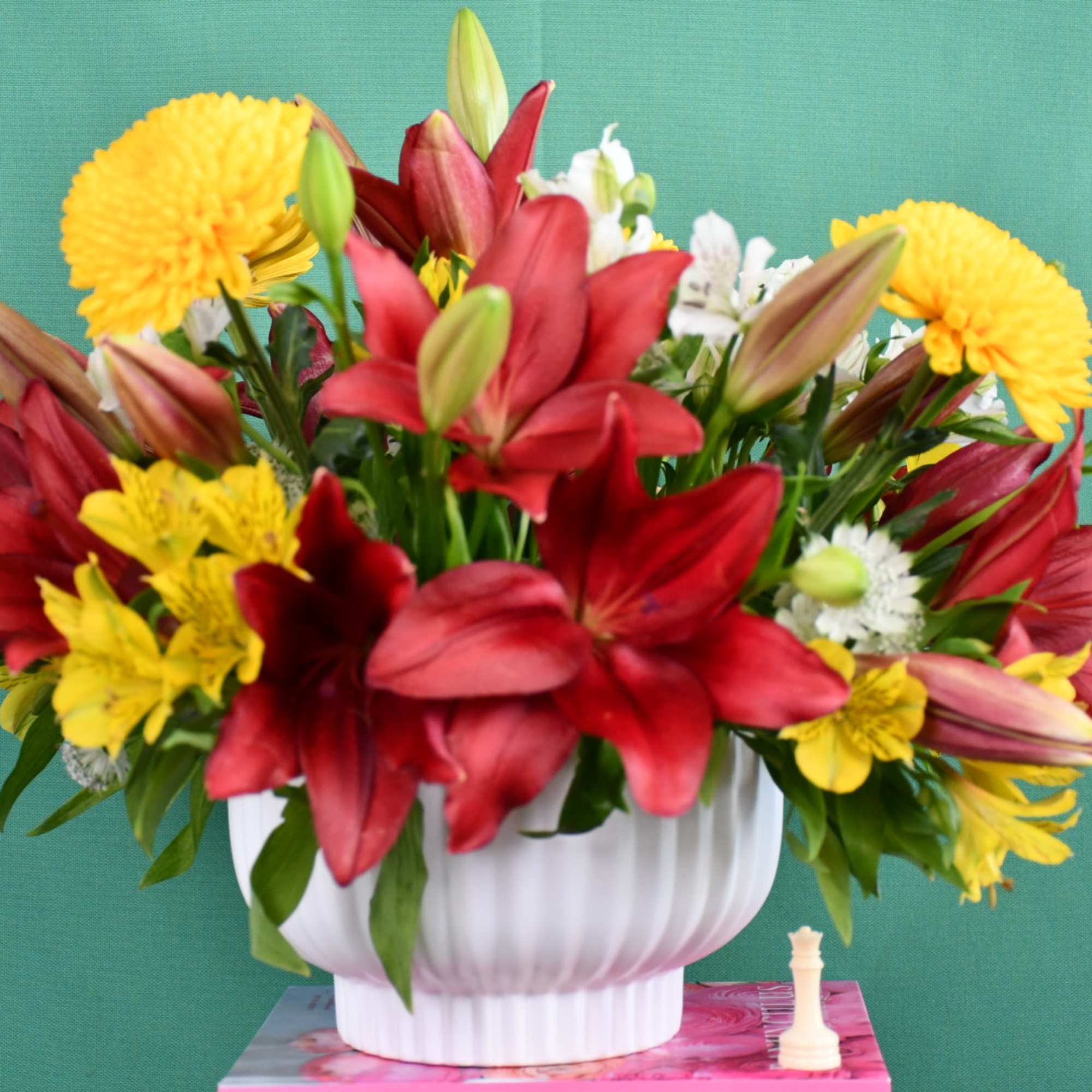 Red lilies and yellow chrysanthemums in a white vase