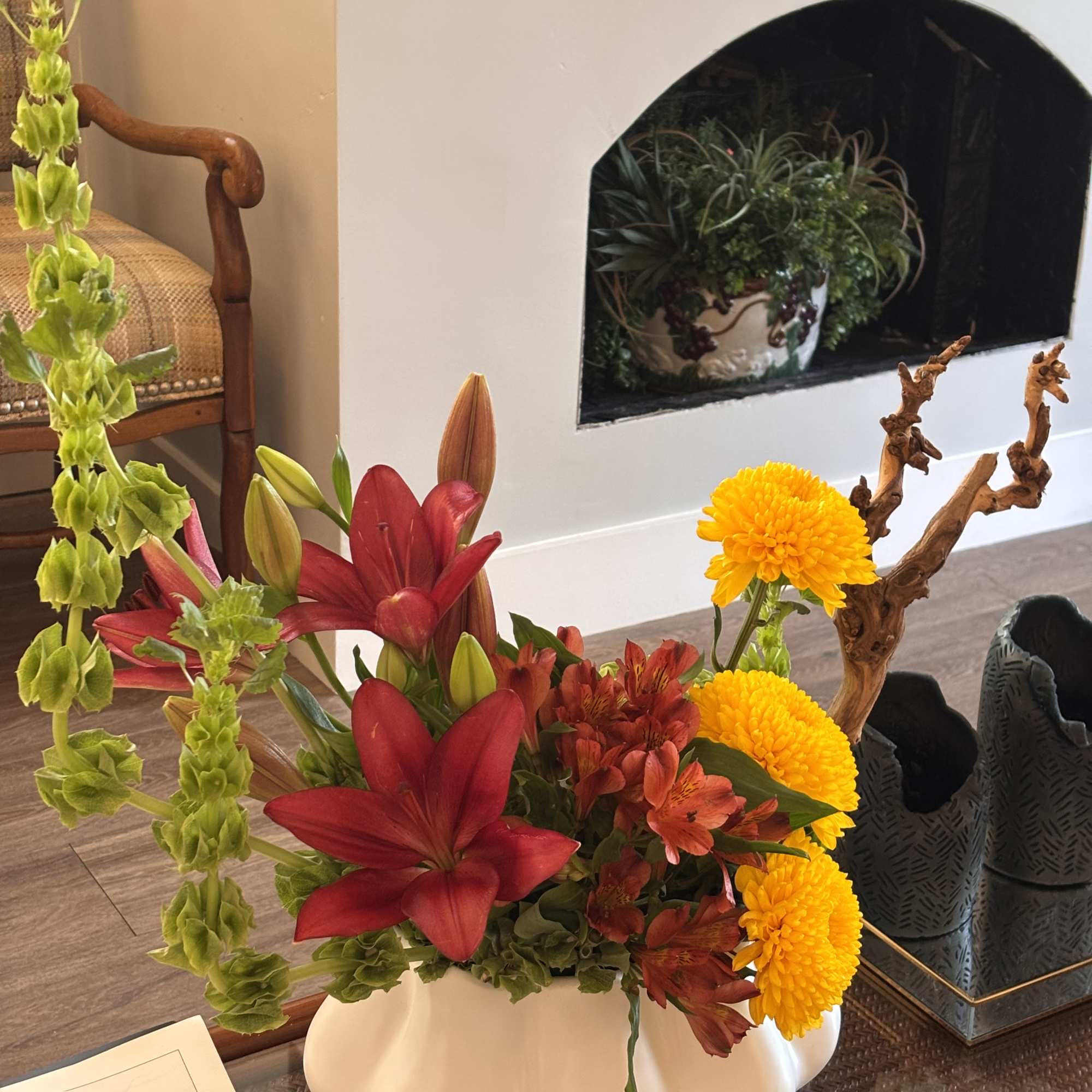 Mixed bouquet with red lilies, yellow chrysanthemums, and orange alstroemeria in a white vase