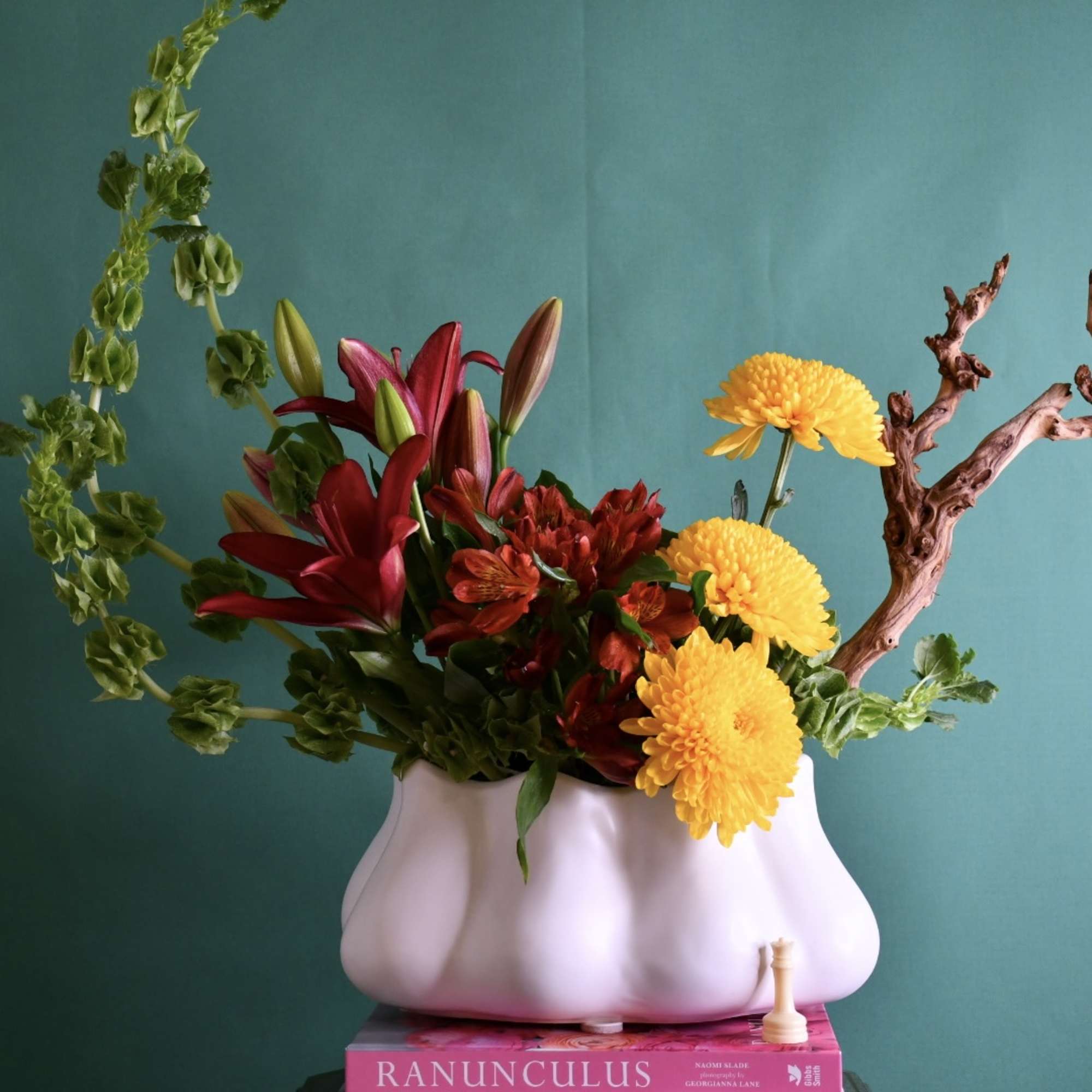 Flower arrangement in a white vase with red lilies and yellow chrysanthemums