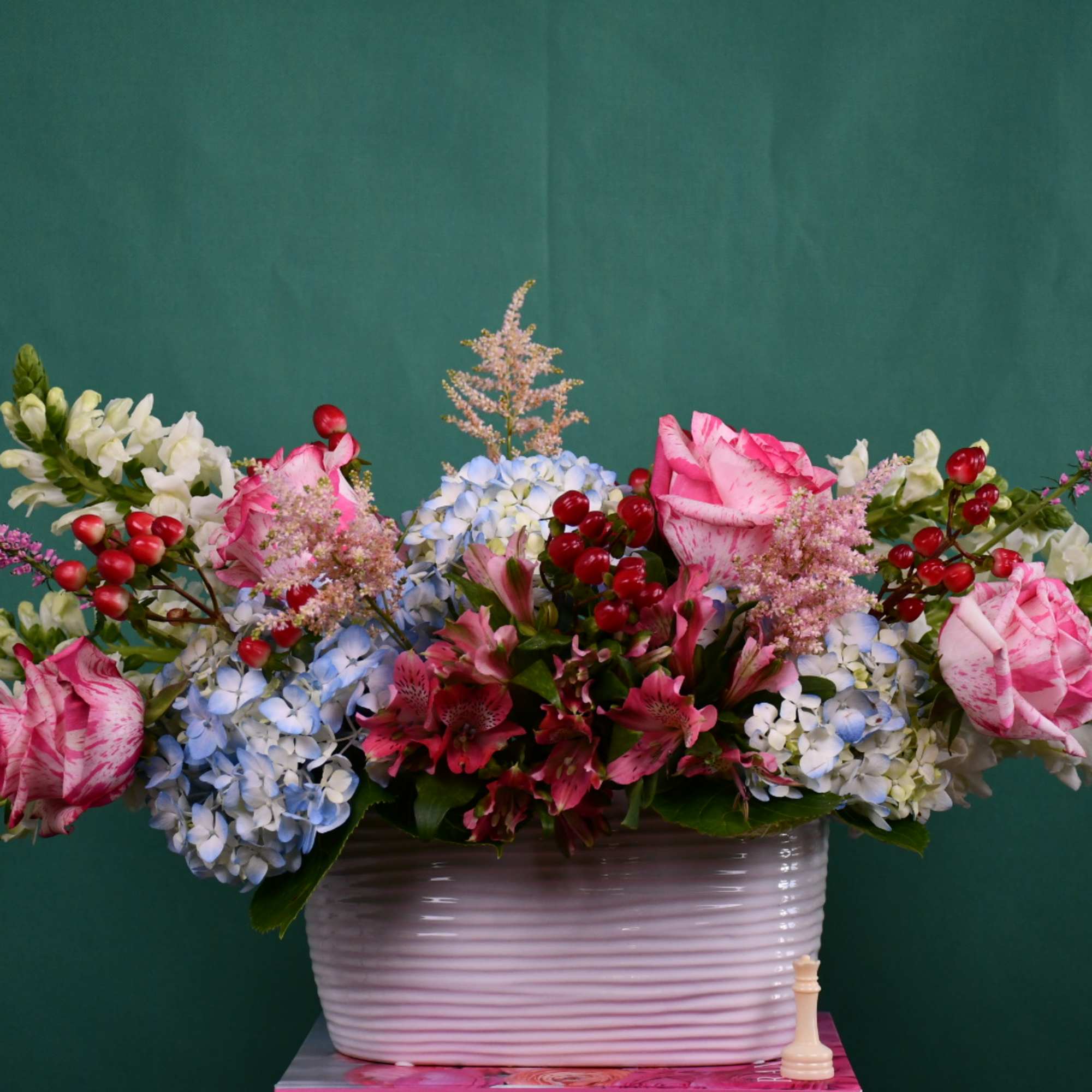 Mixed bouquet of pink roses, blue hydrangeas, and white snapdragons in a white vase