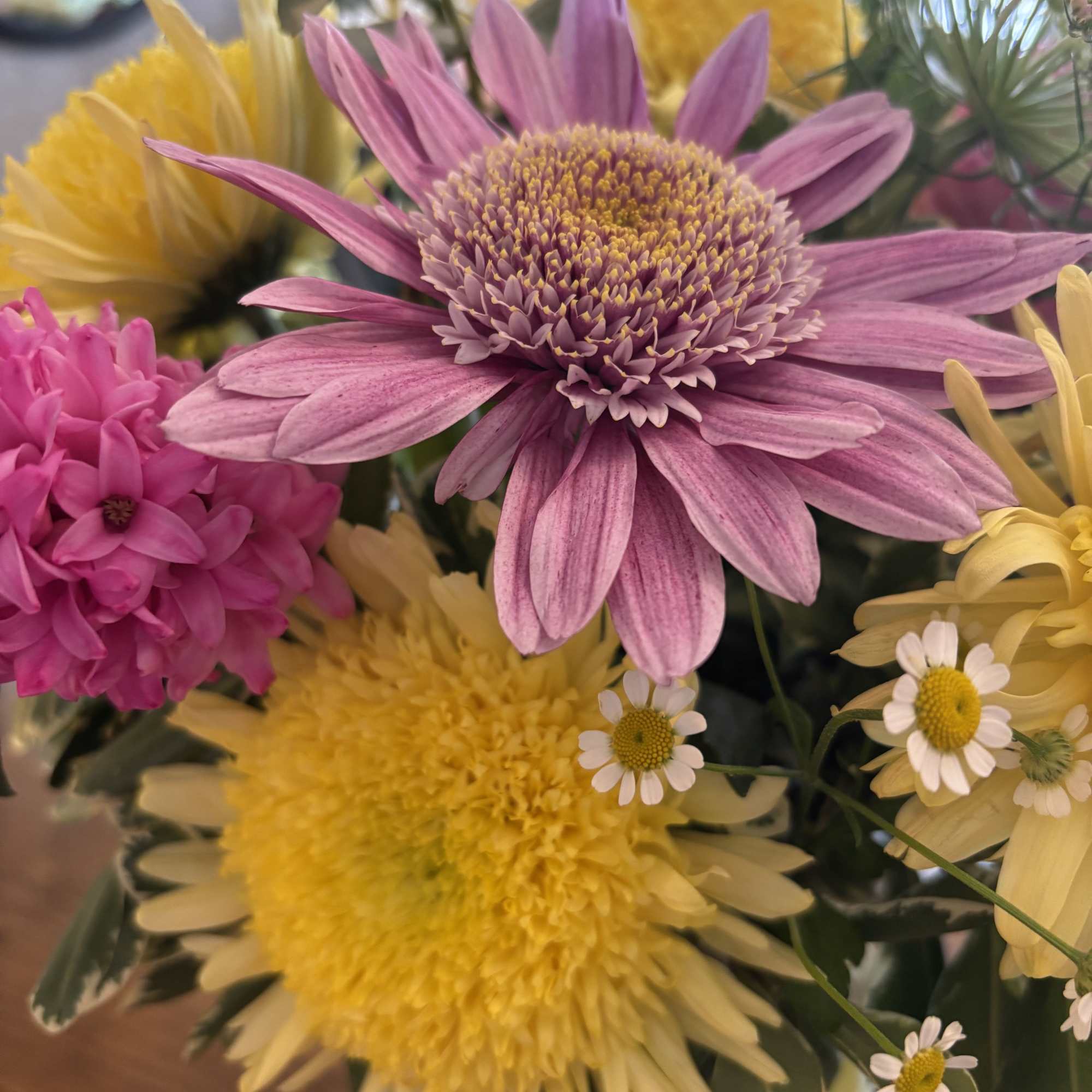 Bouquet of pink, yellow, and white daisies in a glass vase