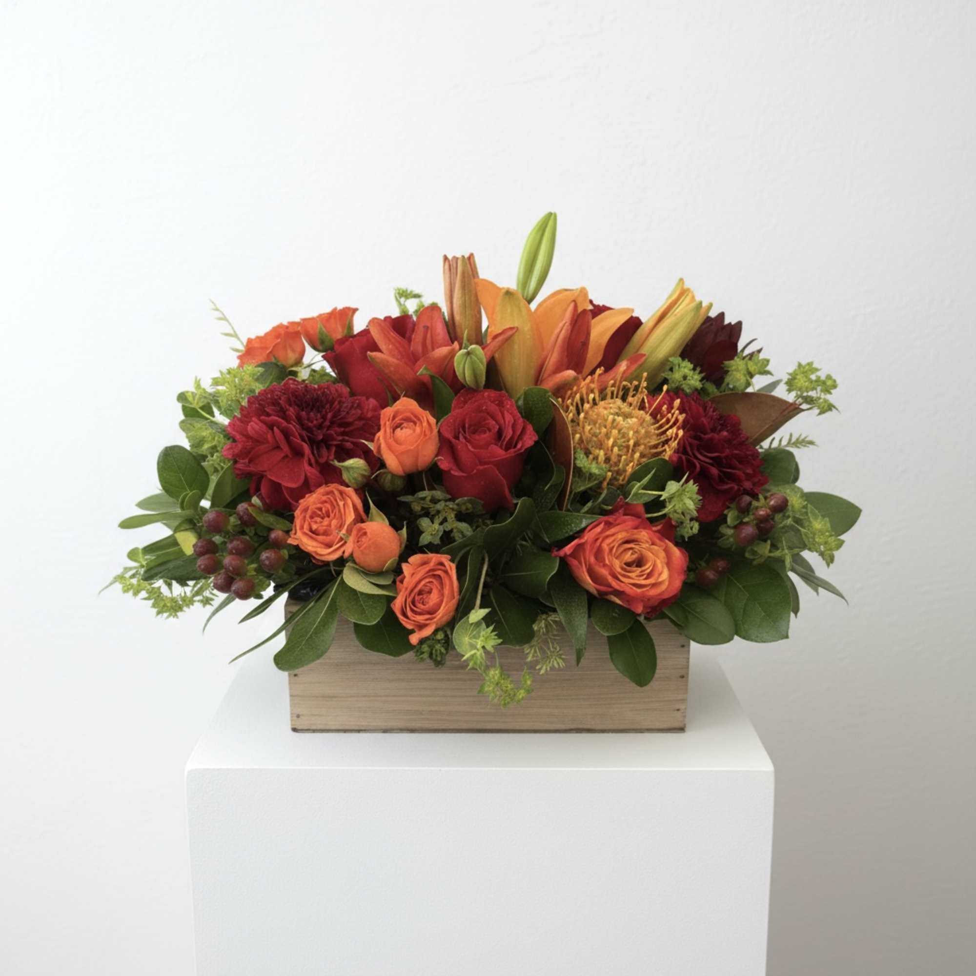 Orange and red floral arrangement in a wooden box