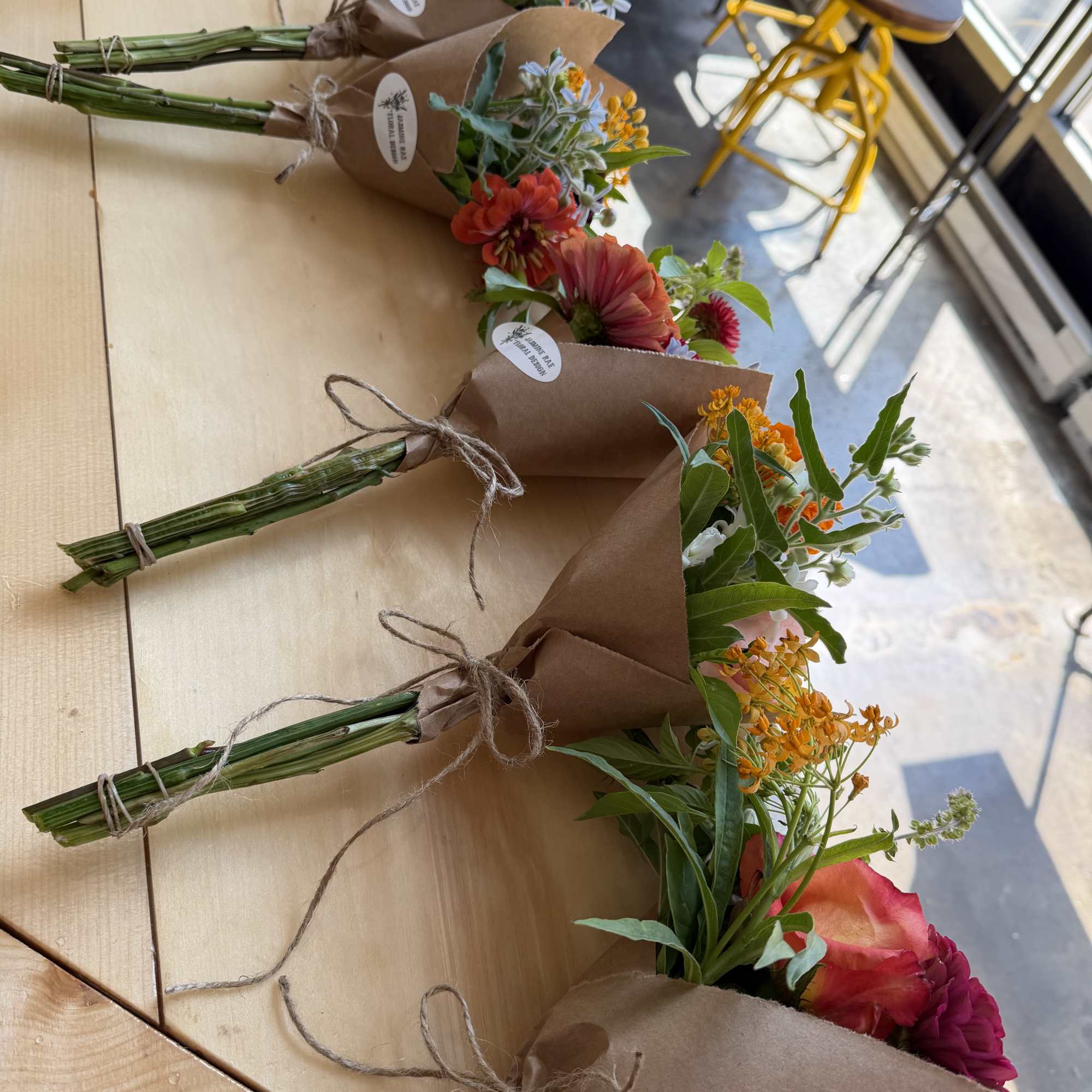 Small wrapped bouquets with orange and pink flowers tied with twine