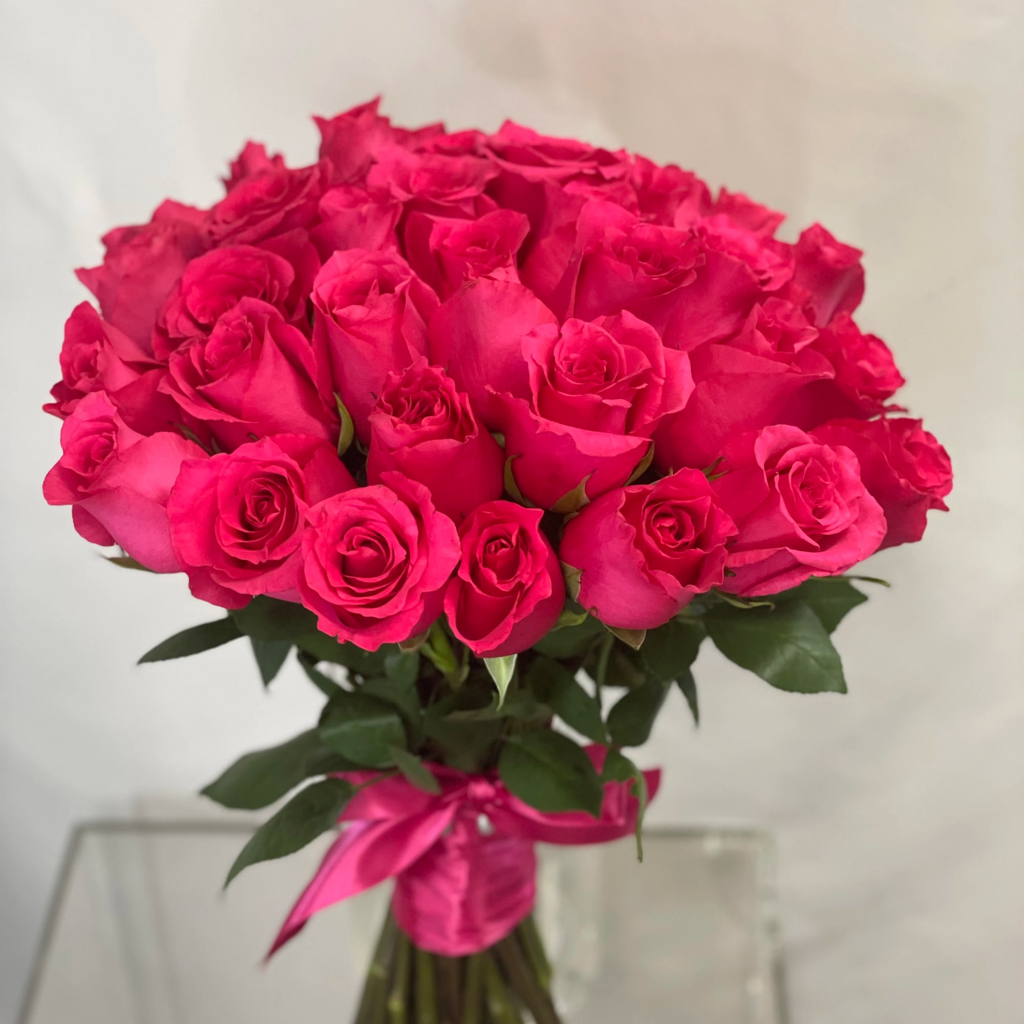 Bouquet of bright pink roses tied with a pink ribbon