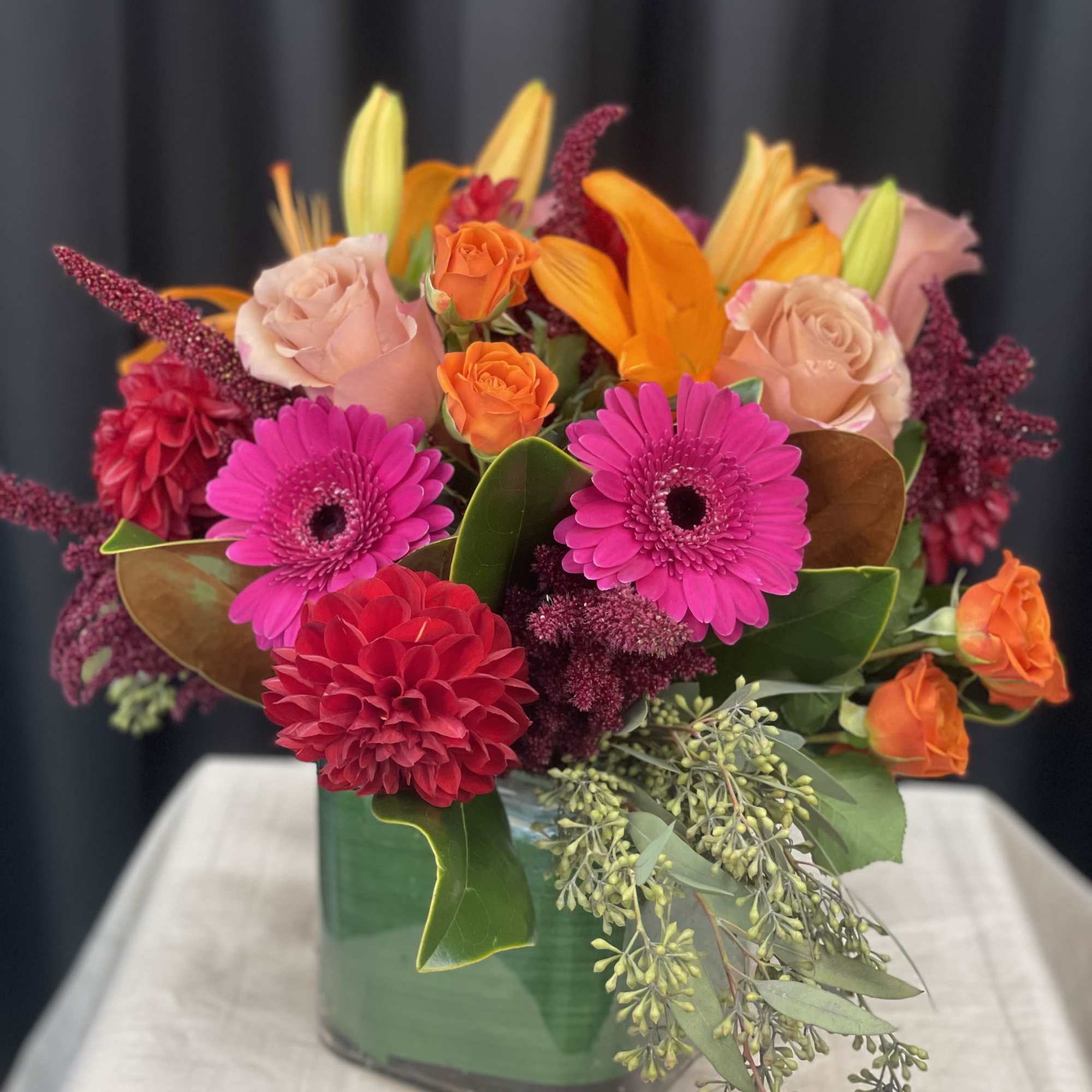 Bright mixed bouquet with pink gerberas, roses, and orange lilies in a vase