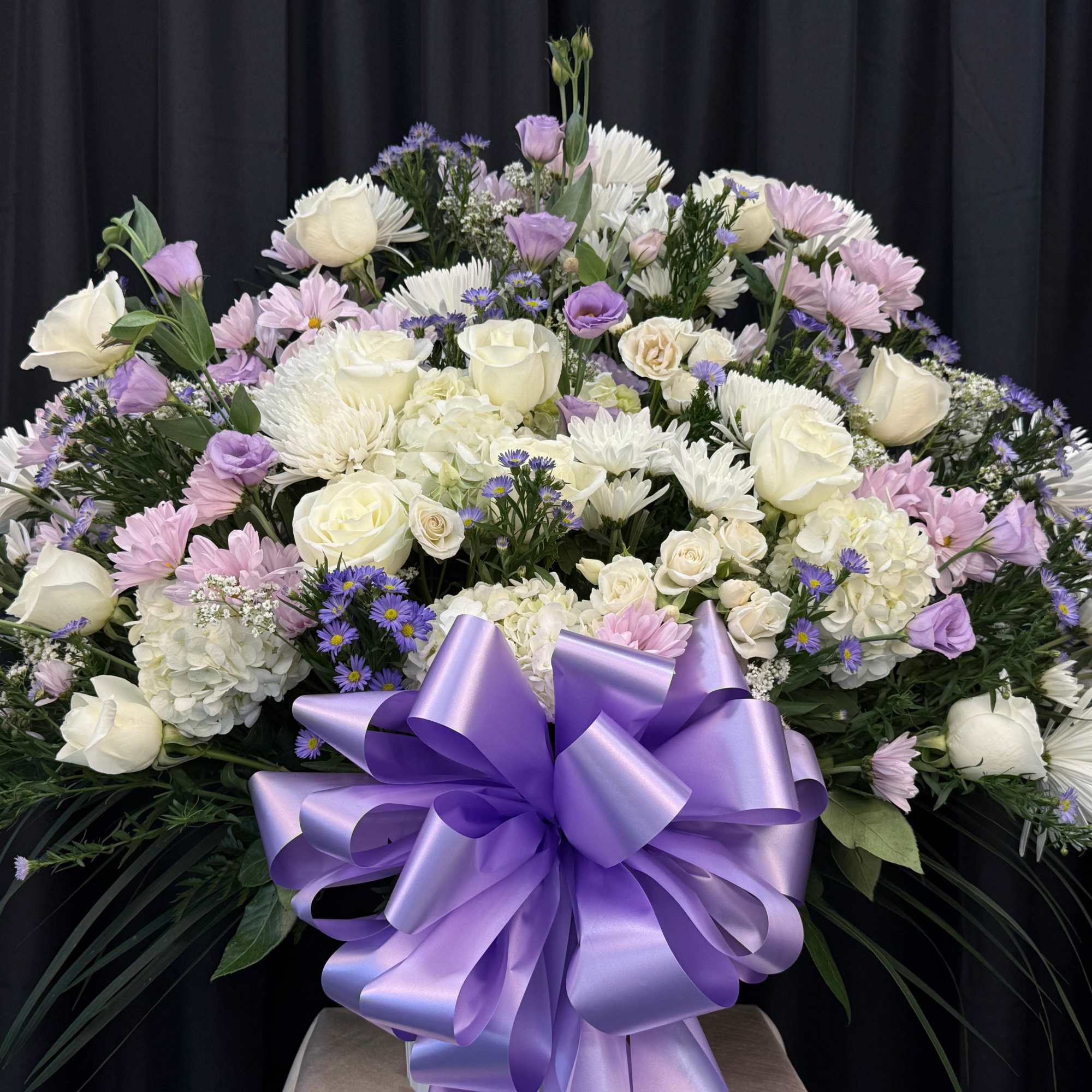 Large bouquet of white and lavender flowers with a purple ribbon