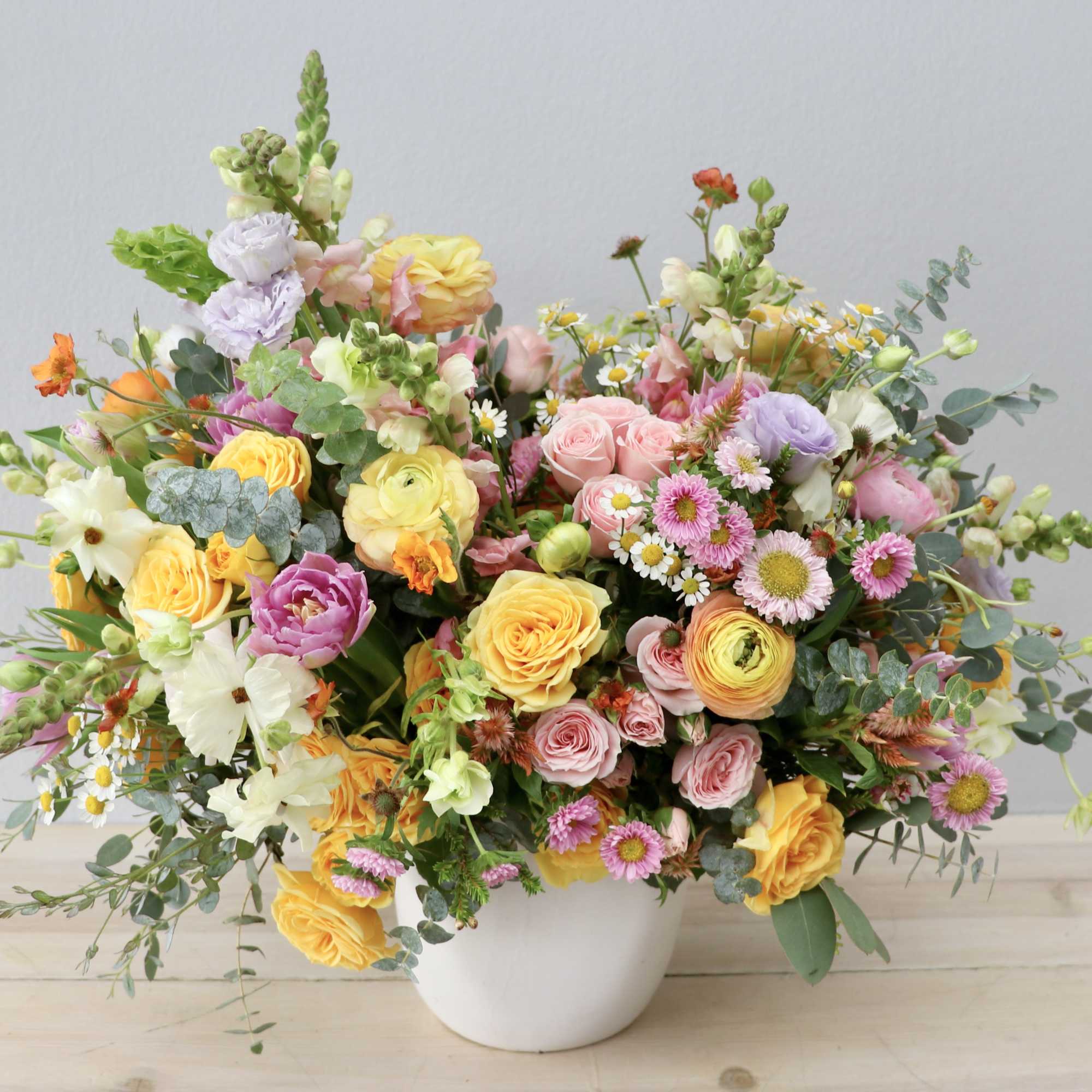 Mixed pastel bouquet in a white vase with roses and daisies