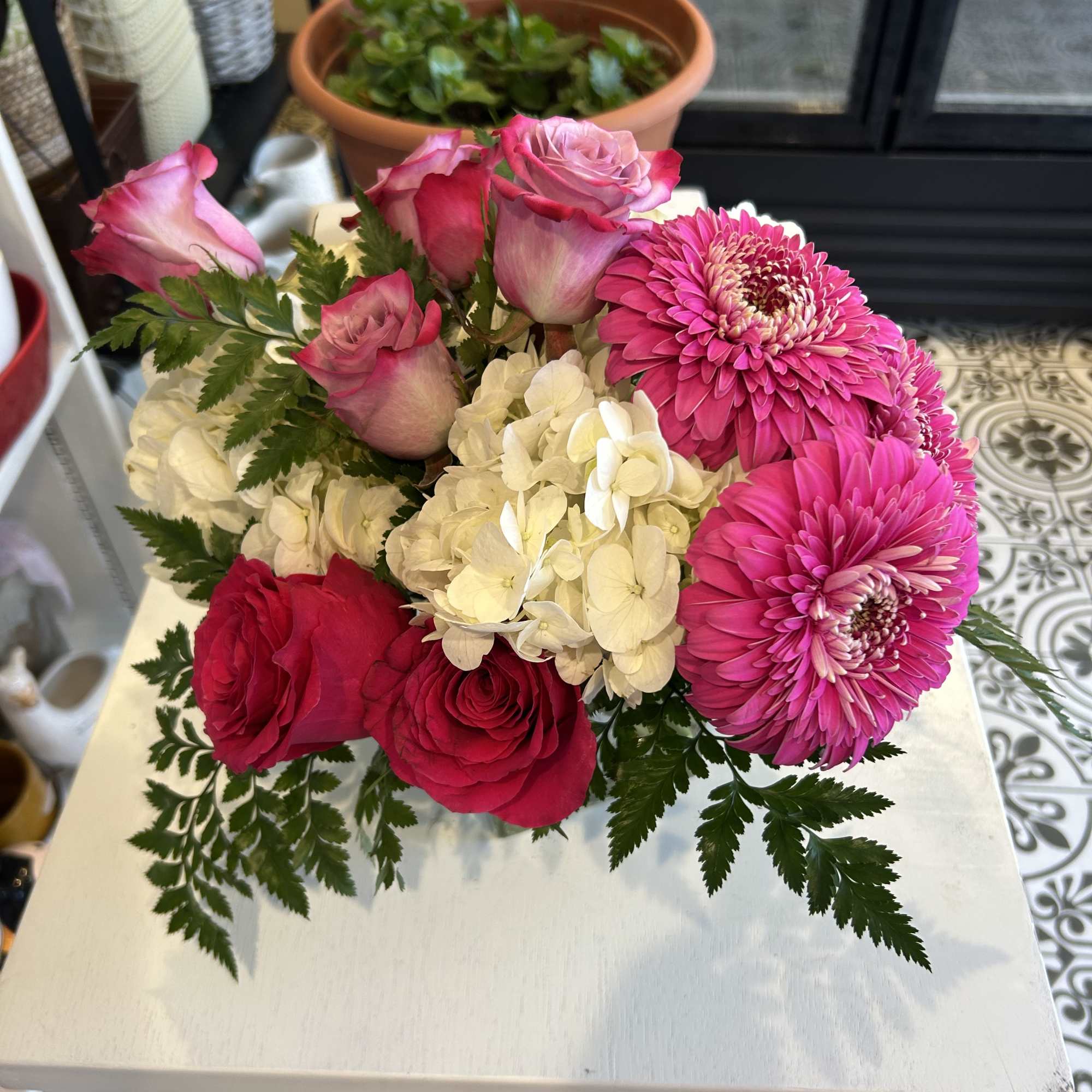 Pink roses and bright pink gerbera daisies with white hydrangea in a low bouquet
