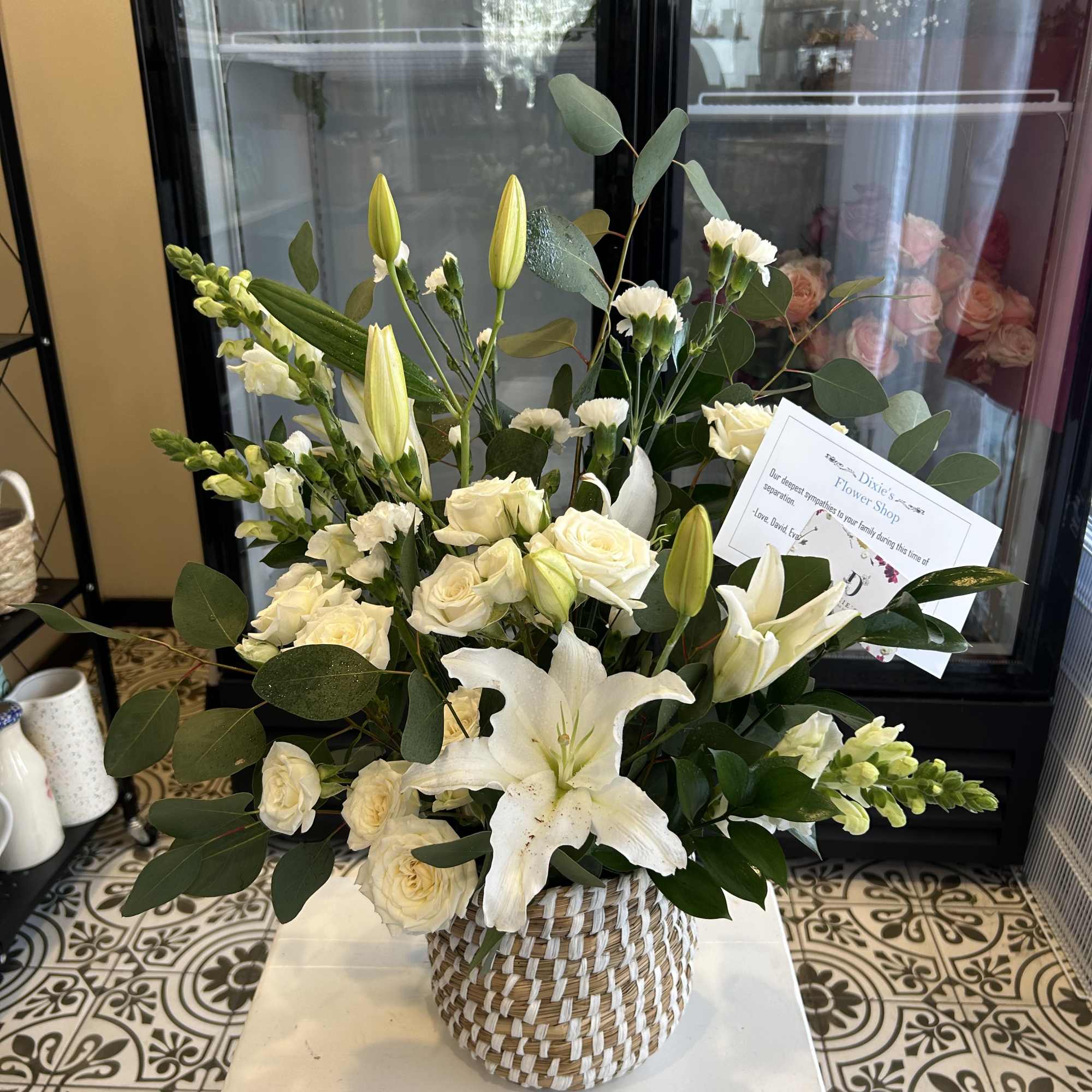 White lilies and cream roses arranged in a woven basket