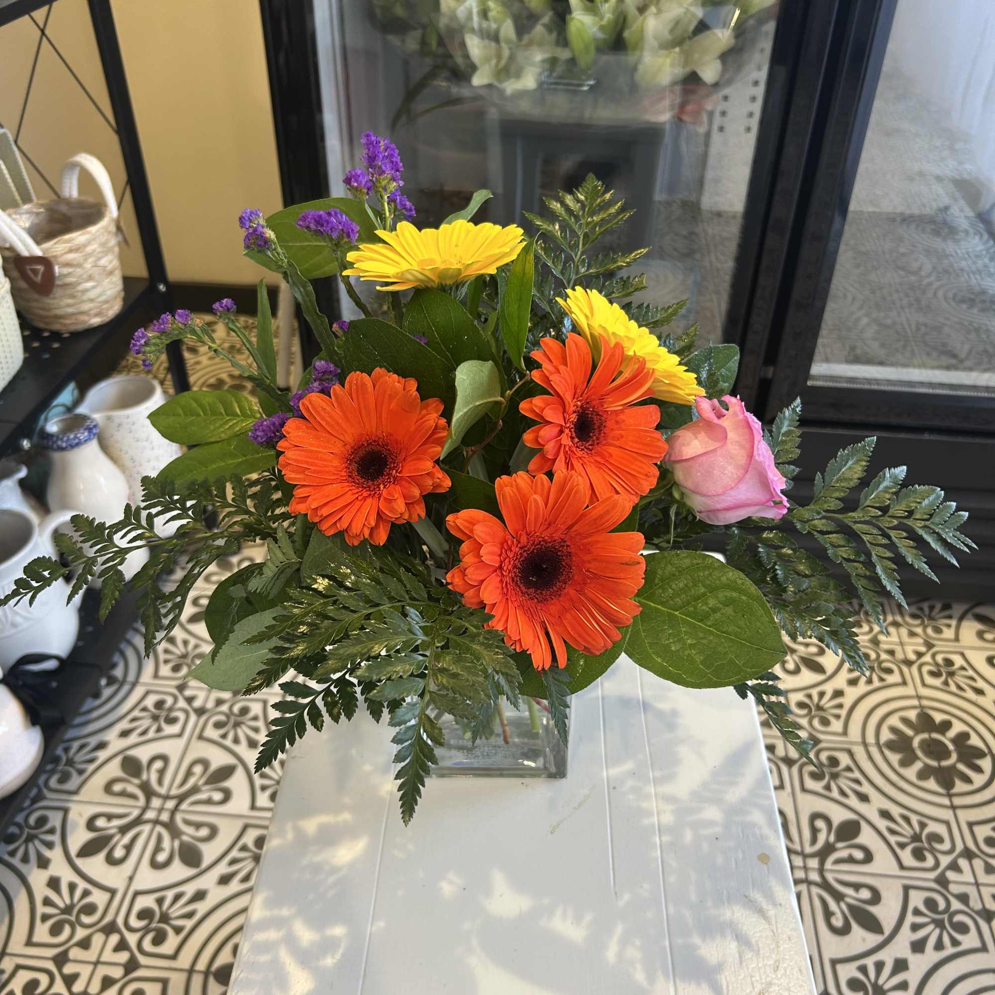 Bright mixed bouquet with orange and yellow daisies in a glass vase