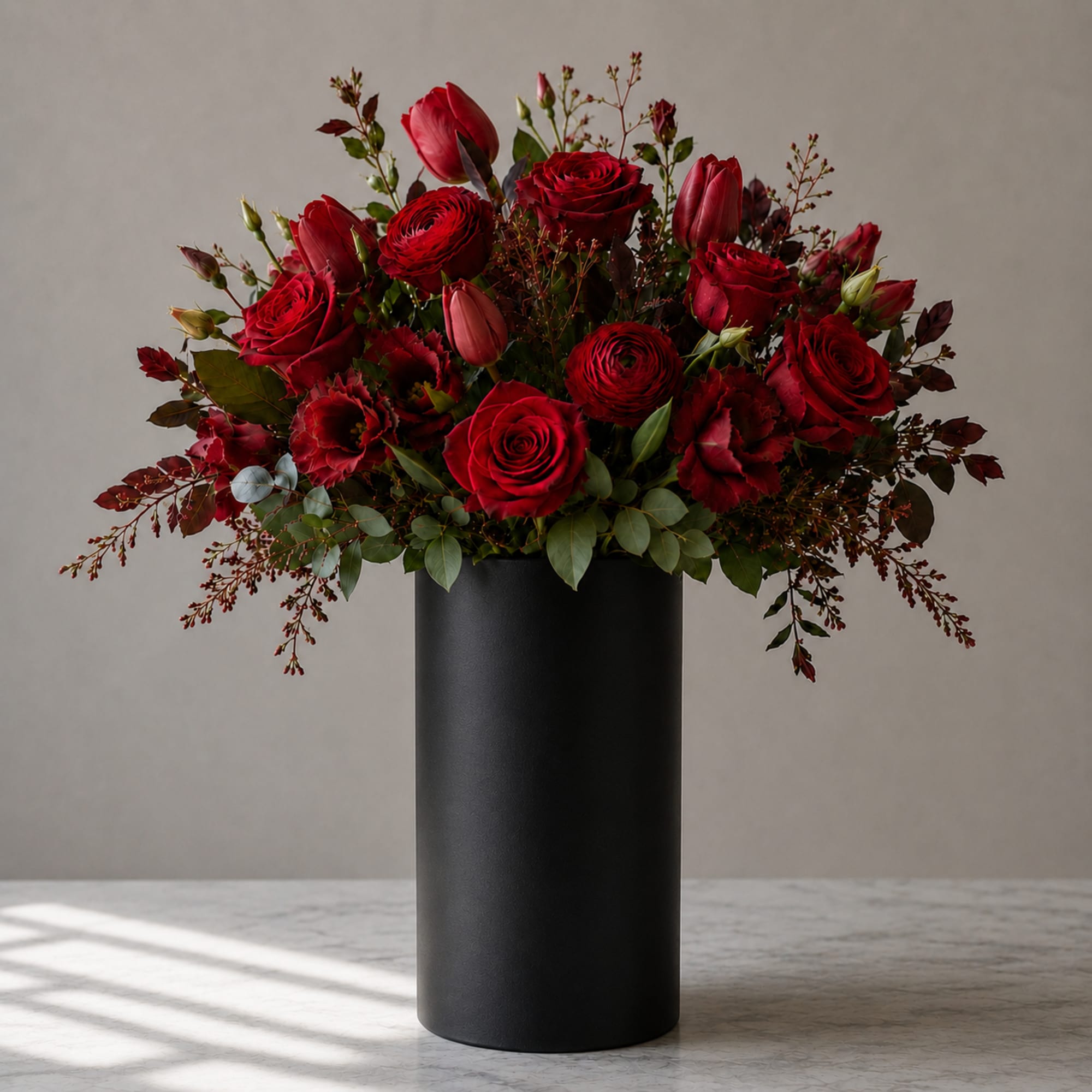 Red roses and tulips arranged in a tall black vase